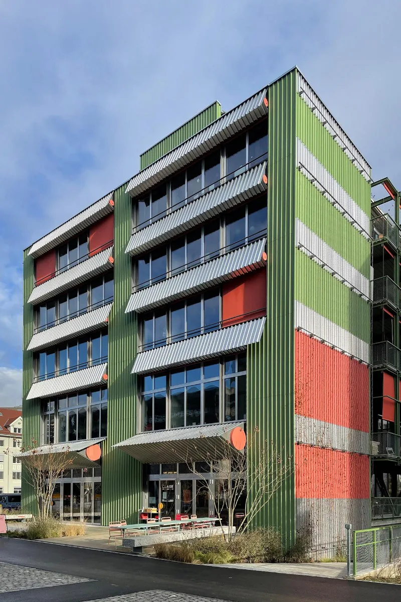 Die beiden Gebäudeenden sind mit bunten Trapezblechen verkleidet.