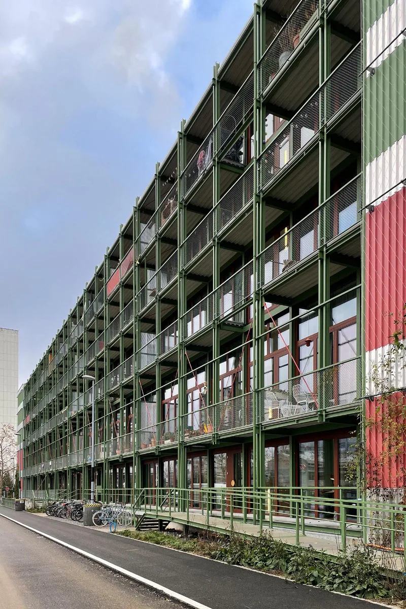 An den Längsseiten sind vor den großen Fensterflächen durchgehende Balkone aus einer Stahlkonstruktion vorgestellt.