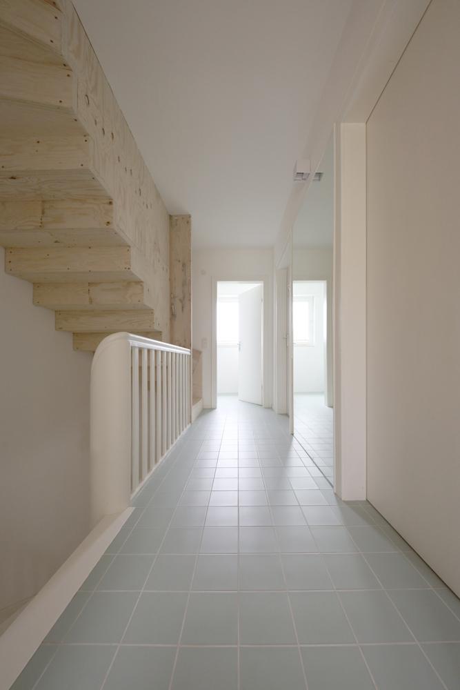 Eine neue Holztreppe führt vom Obergeschoss auf den Dachboden. Ebenso wie die übrigen Holzeinbauten besteht sie aus hellen Mehrschichtplatten.