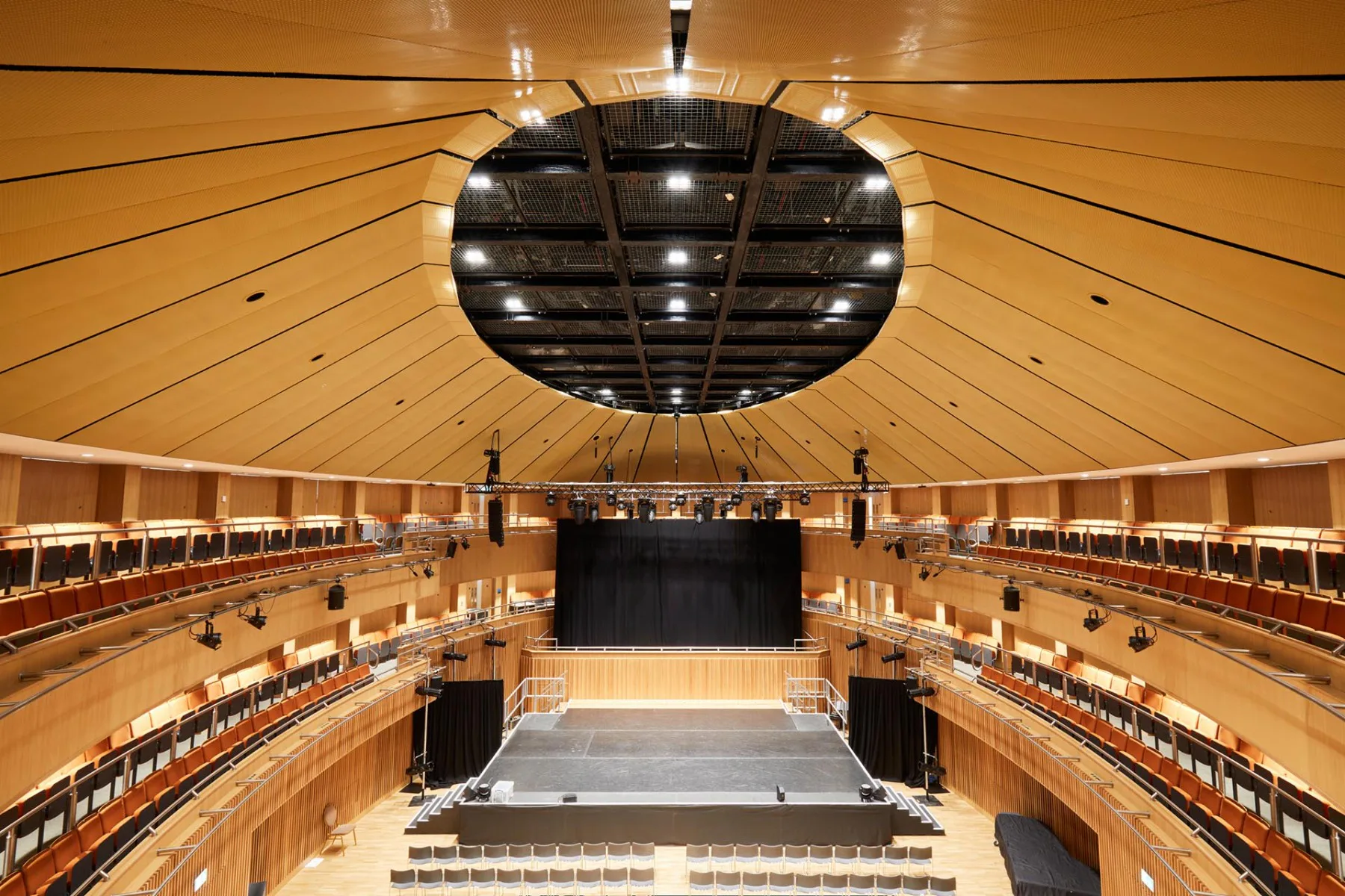 Das Architekturgewebe PC-Alu 6020 optimiert in der St. Edwards School in Oxford die Akustik. Das goldbronzefarbene Finish setzt die Farbgestaltung des Saals an der Decke fort.