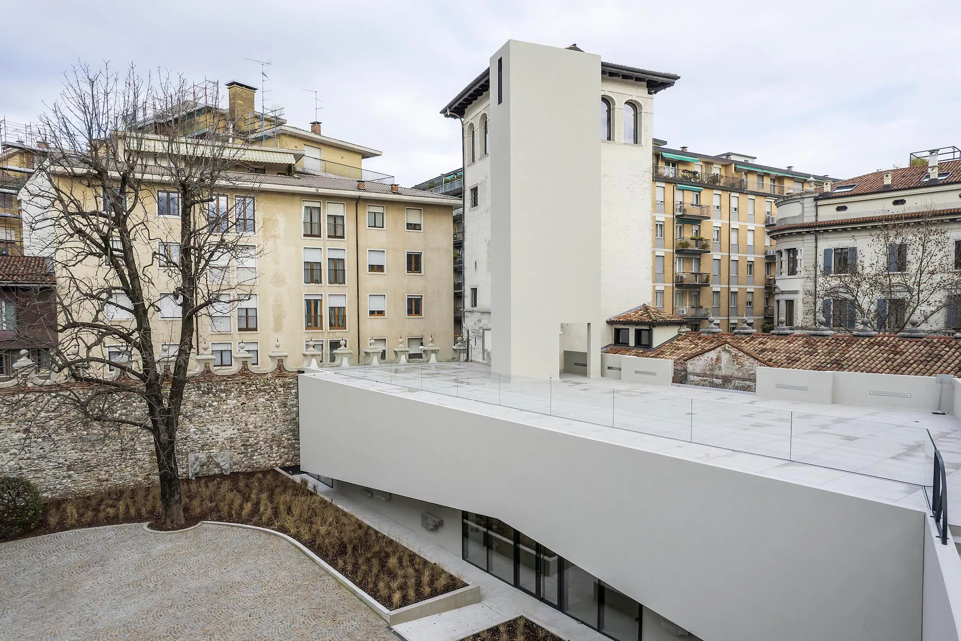 Anbau, Aufzugsturm und Dachterrasse heben sich in homogenem Grau deutlich von den Bestandsstrukturen ab.