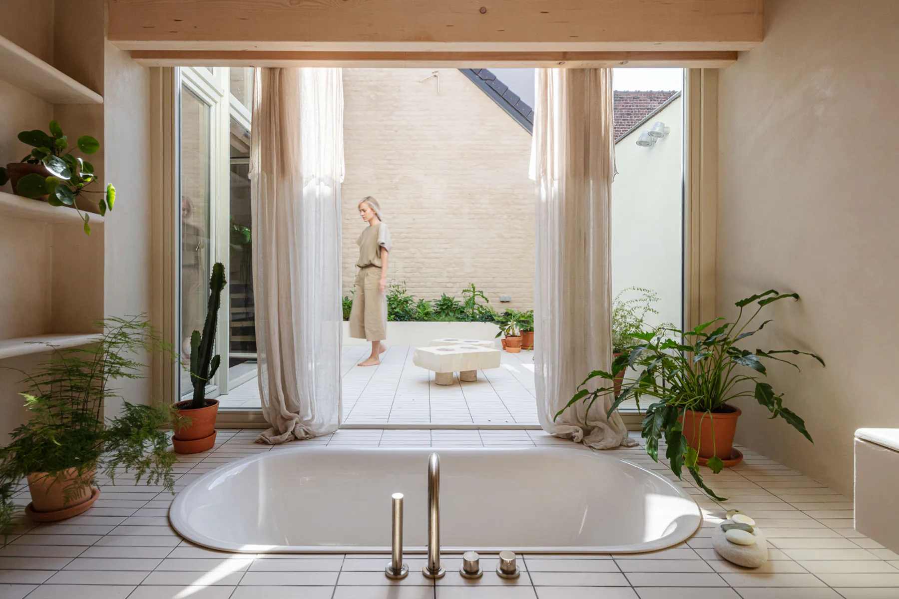 Die Fließen auf der Ebene der Badewanne ziehen sich auf die Terrasse weiter und verbinden Innenraum und Außenraum.