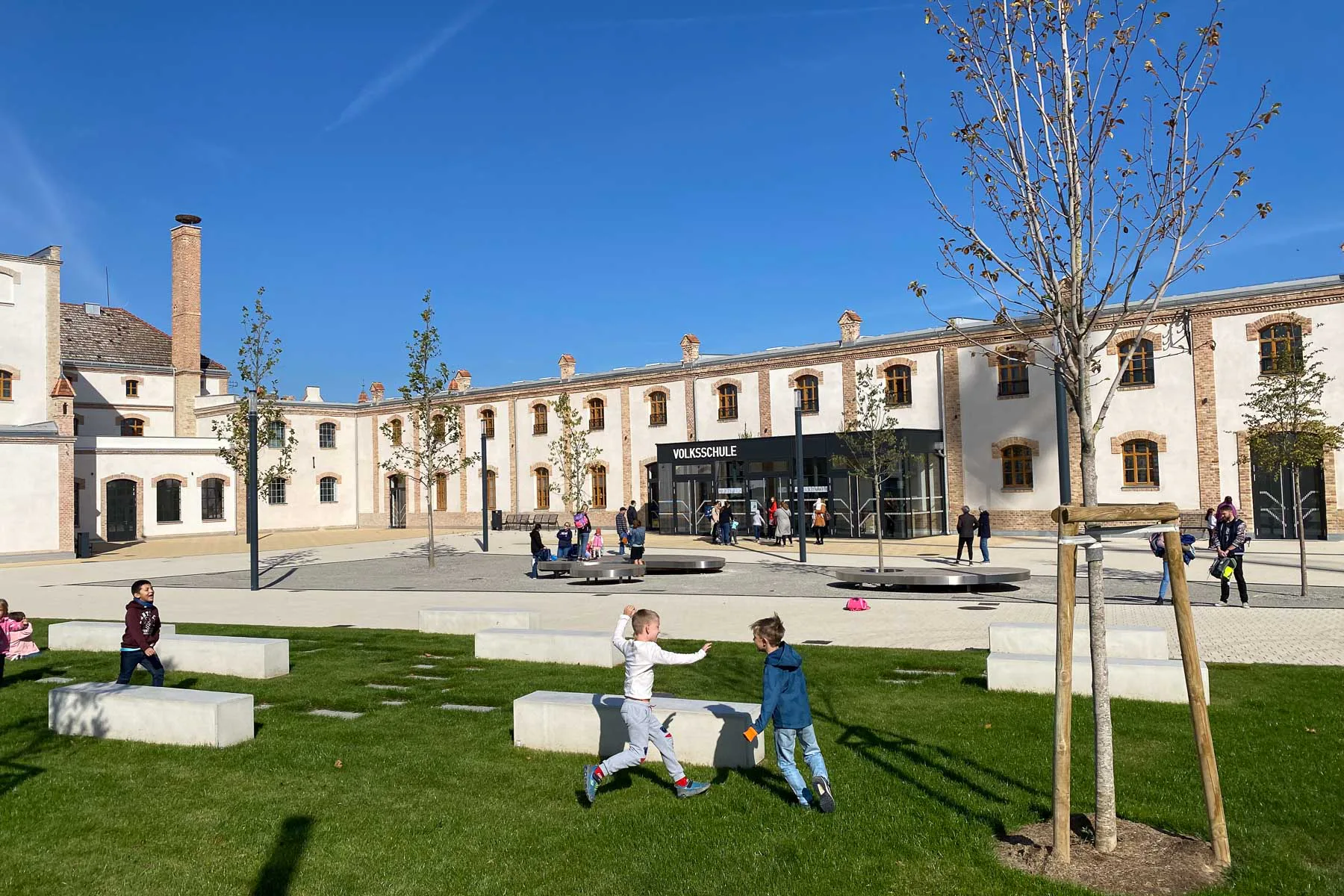 Statt Versiegelung neuer Grünfläche: Am Gelände der ehemaligen Erbsenfabrik in Bruckneudorf entstehen durch Um- und Neubauten von Pesendorfer | Machalek | Dolmanits Architekten eine Volksschule, Reihenhäuser, Wohnungen, Büros und Geschäfte.