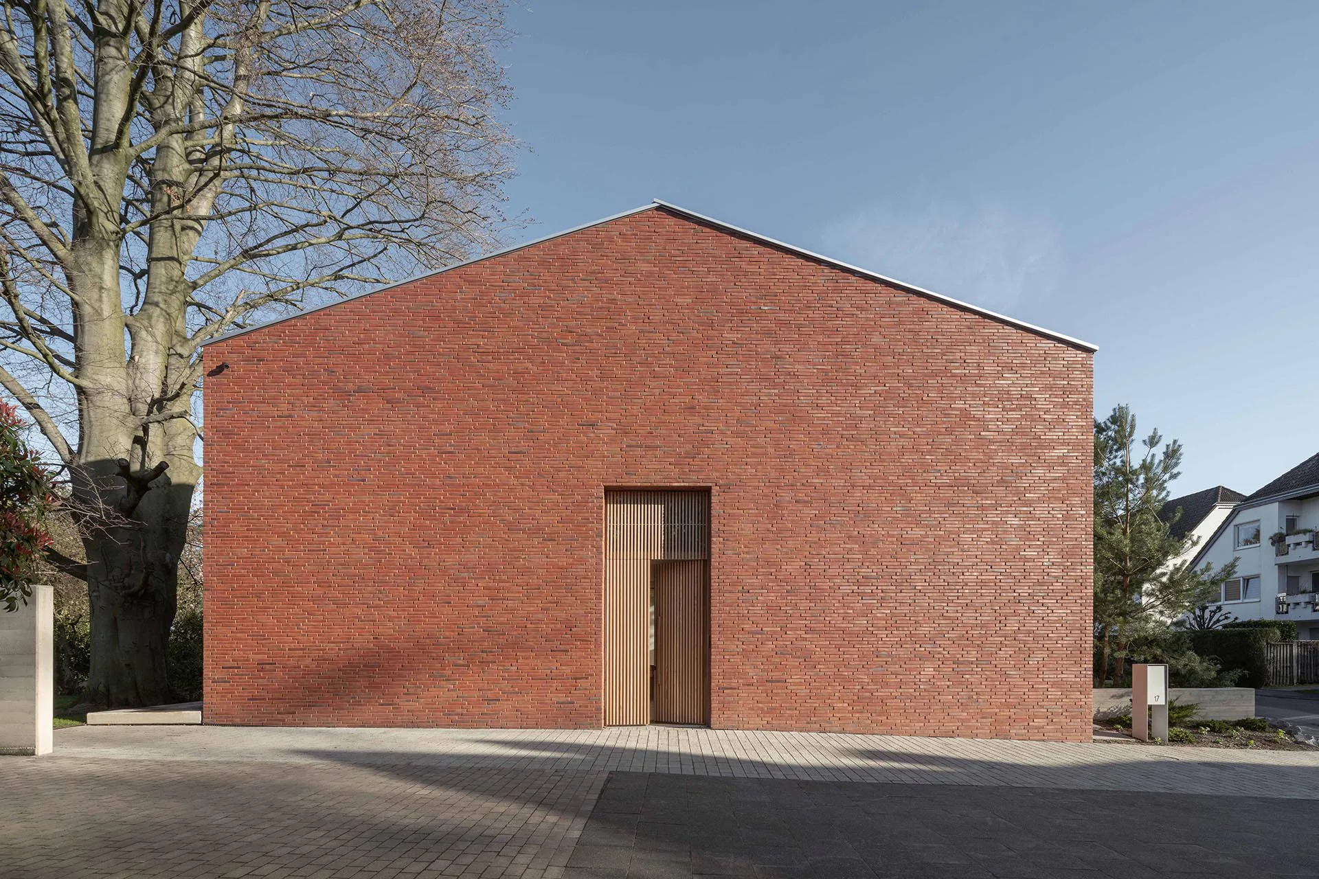 Die Klinkerfassade Richtung Süden ist bis auf das überhöhte Entree aus Holz vollständig geschlossen.