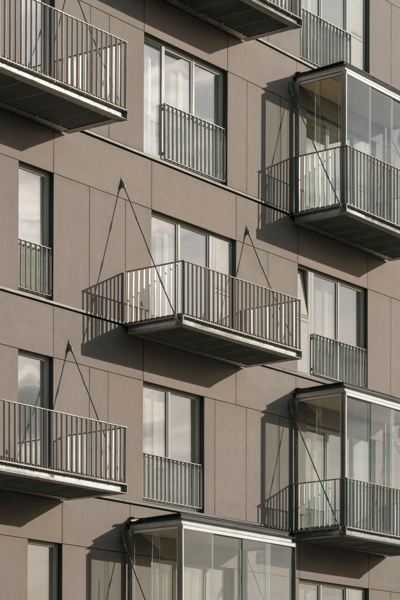 Hochschalldämmende Fenster zur Straße gewährleisten niedrige Schallpegel innerhalb der Wohnungen. Faserzementplatten verkleiden die Fassade.