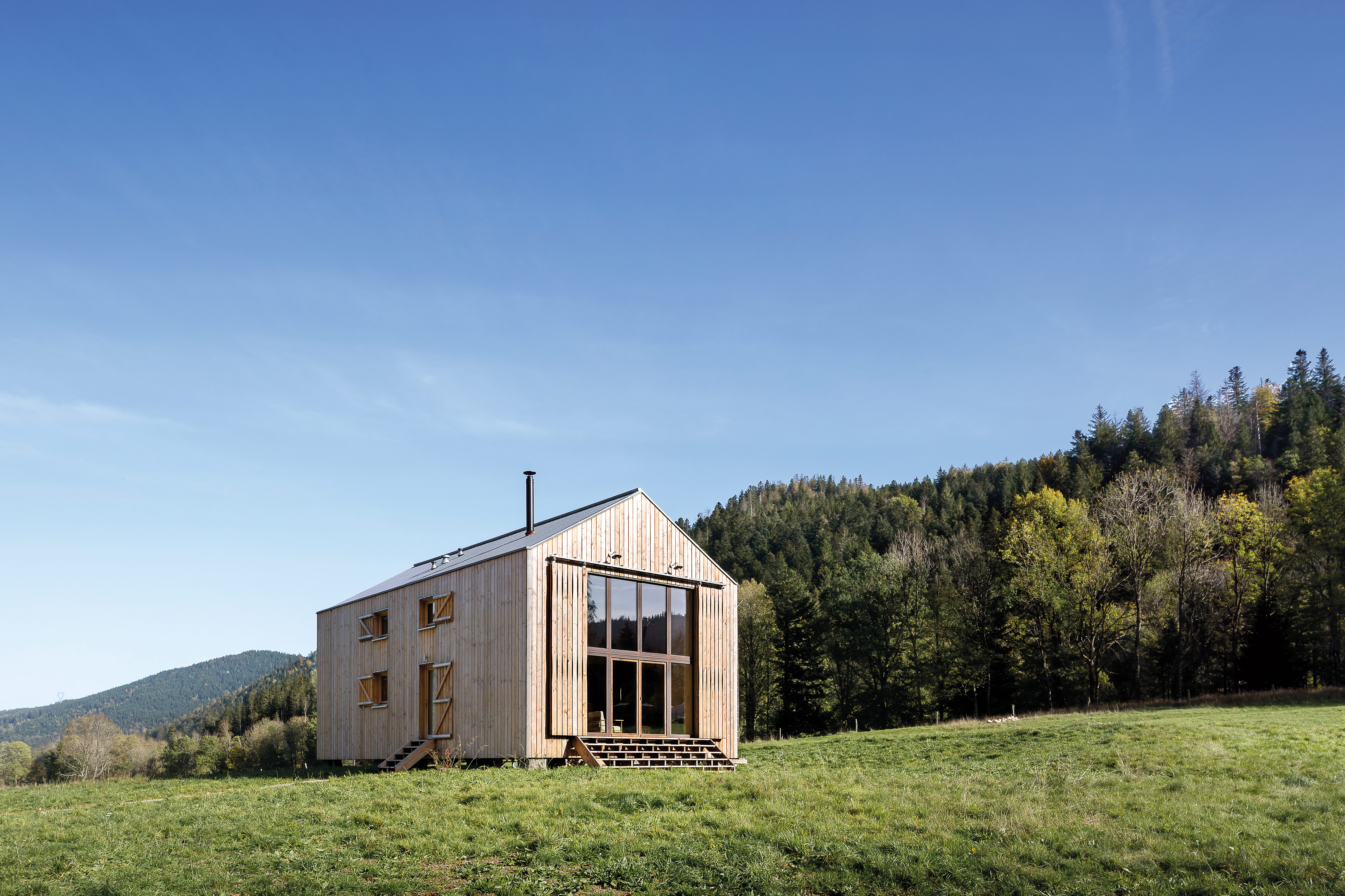 Wie eine bewohnbare Scheune steht das Ferienhaus auf einem Naturgrundstück in den Vogesen. Es ist aus Holz und Stroh gebaut, das aus der Umgebung stammt.