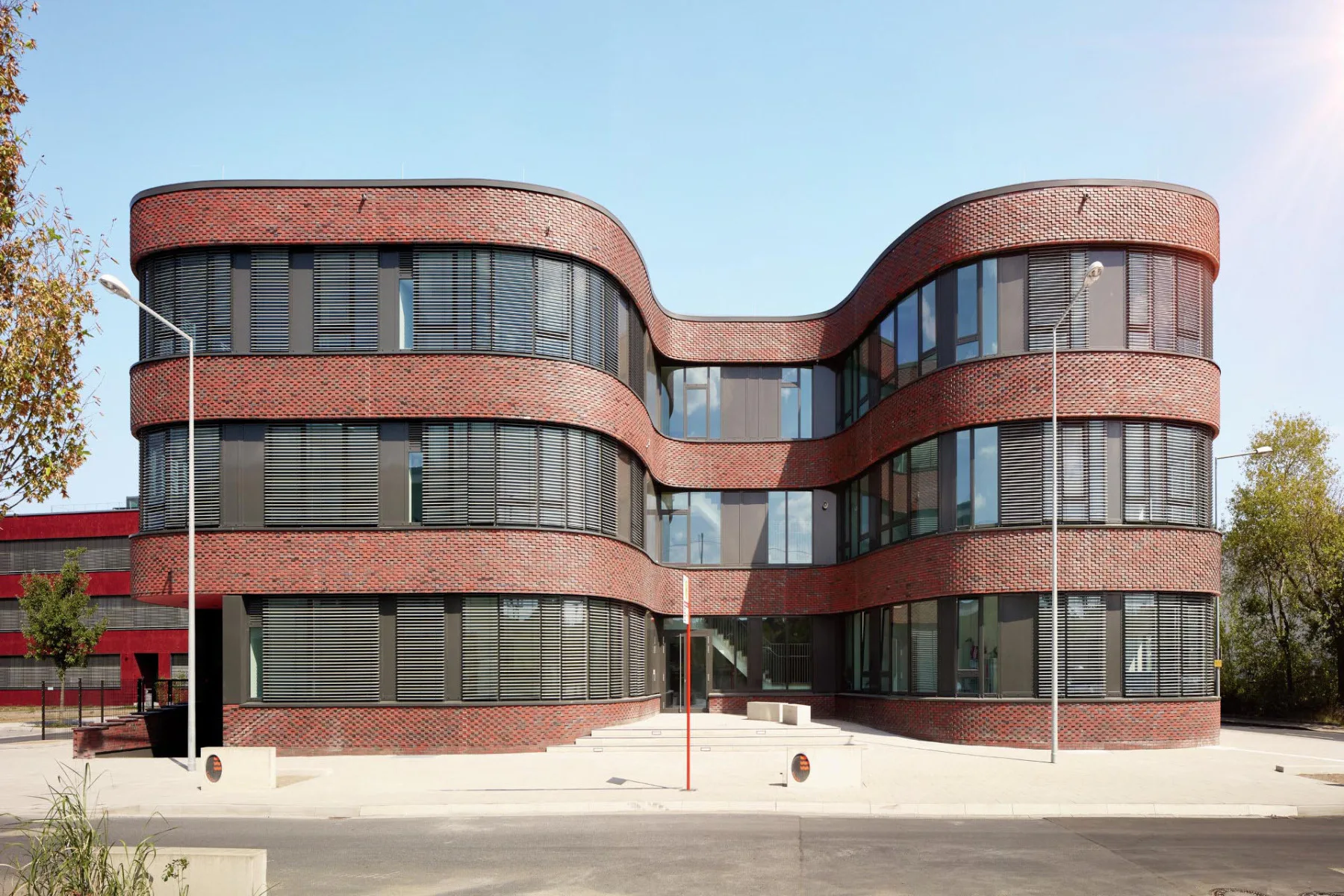 Der geschwungene Baukörper des multifunktionalen Gebäudes im Gewerbe- und Landschaftspark Triotop Köln wurde mit intelligent gesteuerten Warema Raffstoren ausgestattet, so dass die Innenräume vor zu viel Sonne geschützt sind.