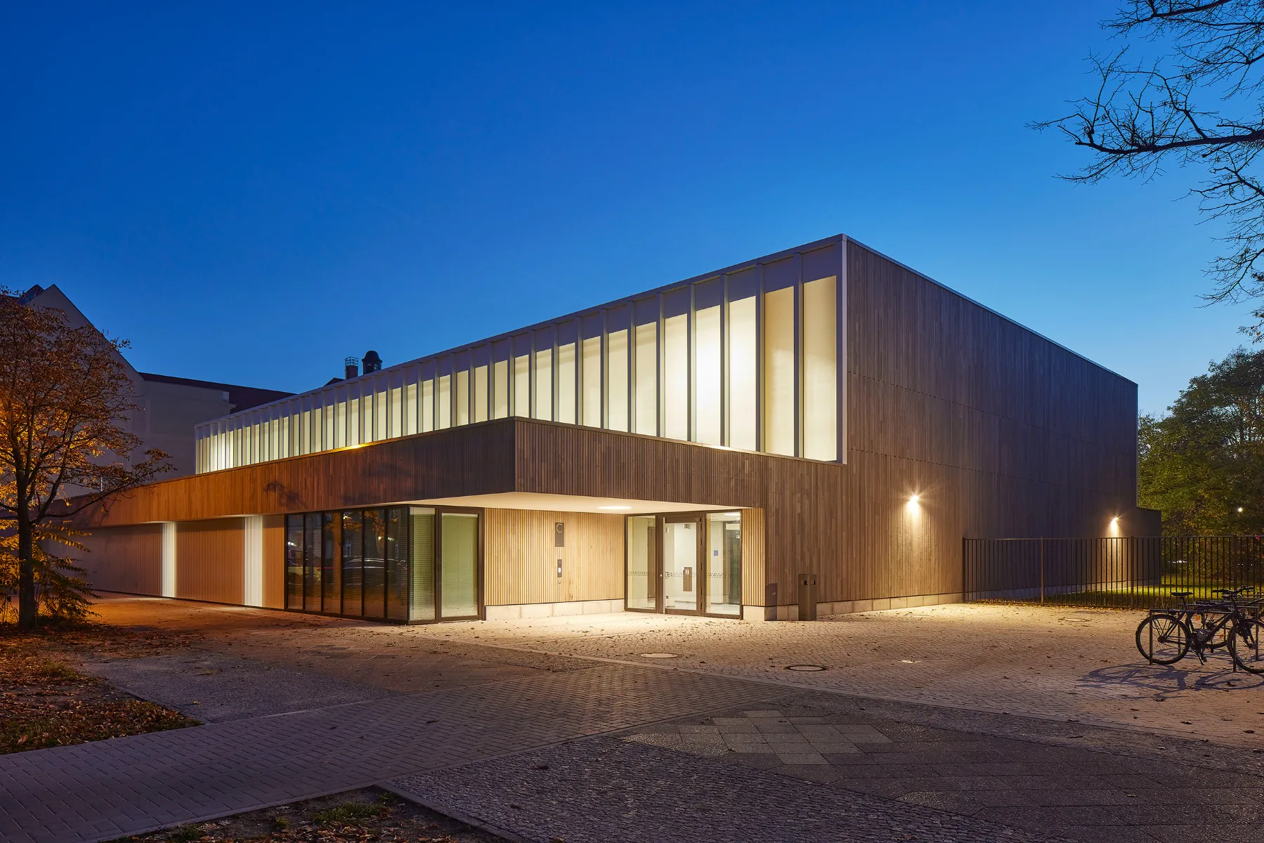 Die hohe Sporthalle wird von zwei niedrigeren Baukörpern längsseitig gefasst.