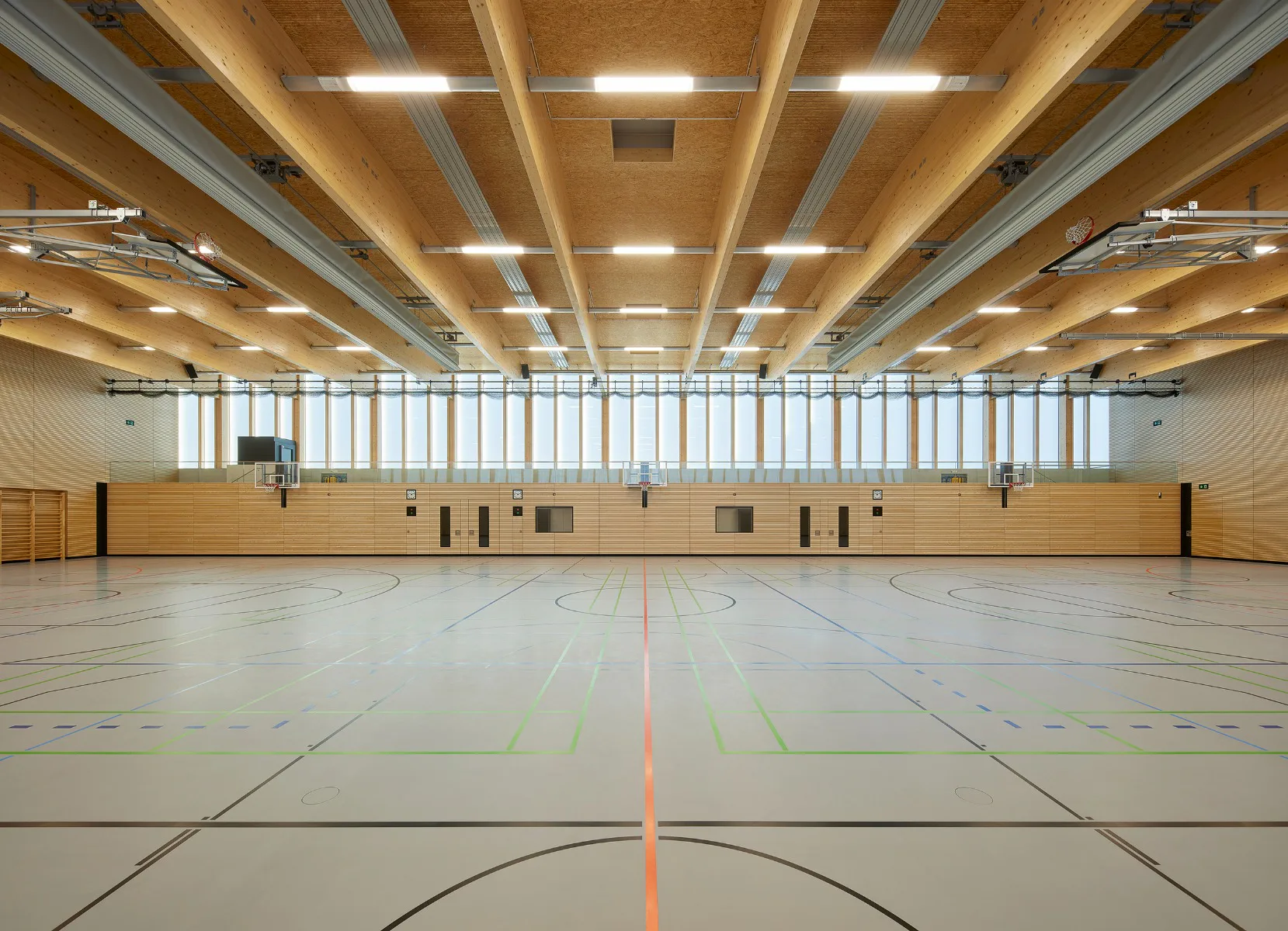 Die Tragwerkselemente aus Brettschichtholz und die horizontal lamellierten Prallwände prägen den Innenraum.