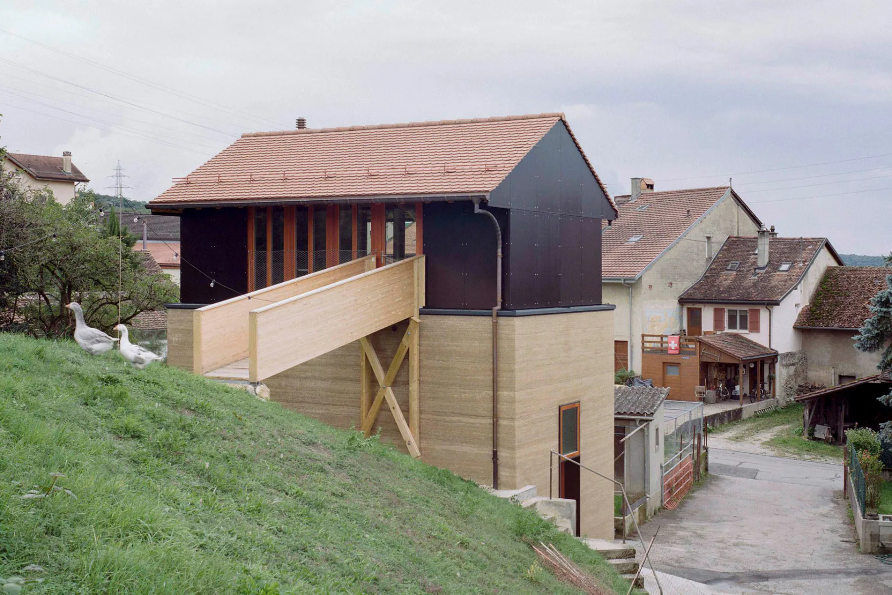 Eine kleine Holzbrücke führt in das neu entstandene Obergeschoss des Wohnhauses La Recette.
