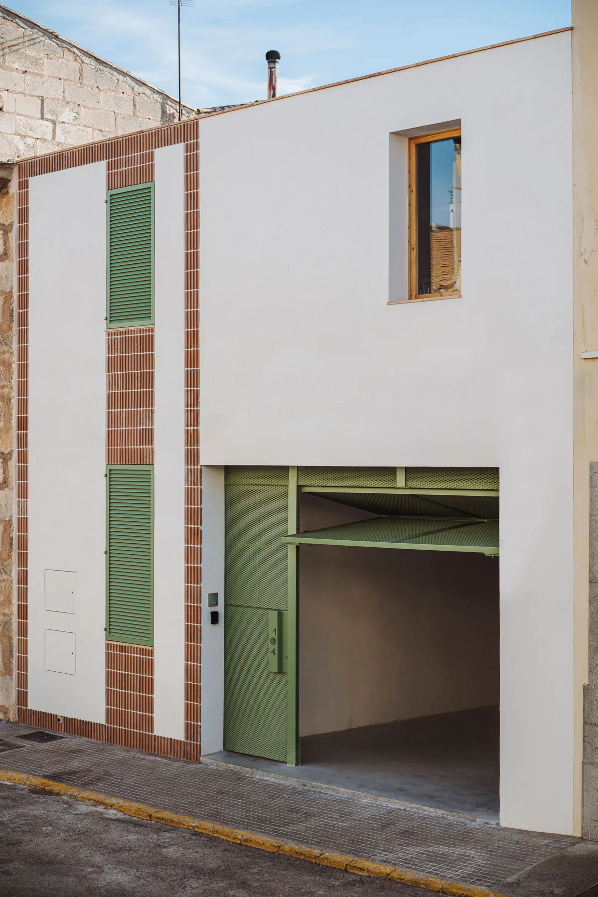 Ein grünes Metalltor an der vorderen Fassade sorgt für eine natürliche Belüftung der unteren Etage.