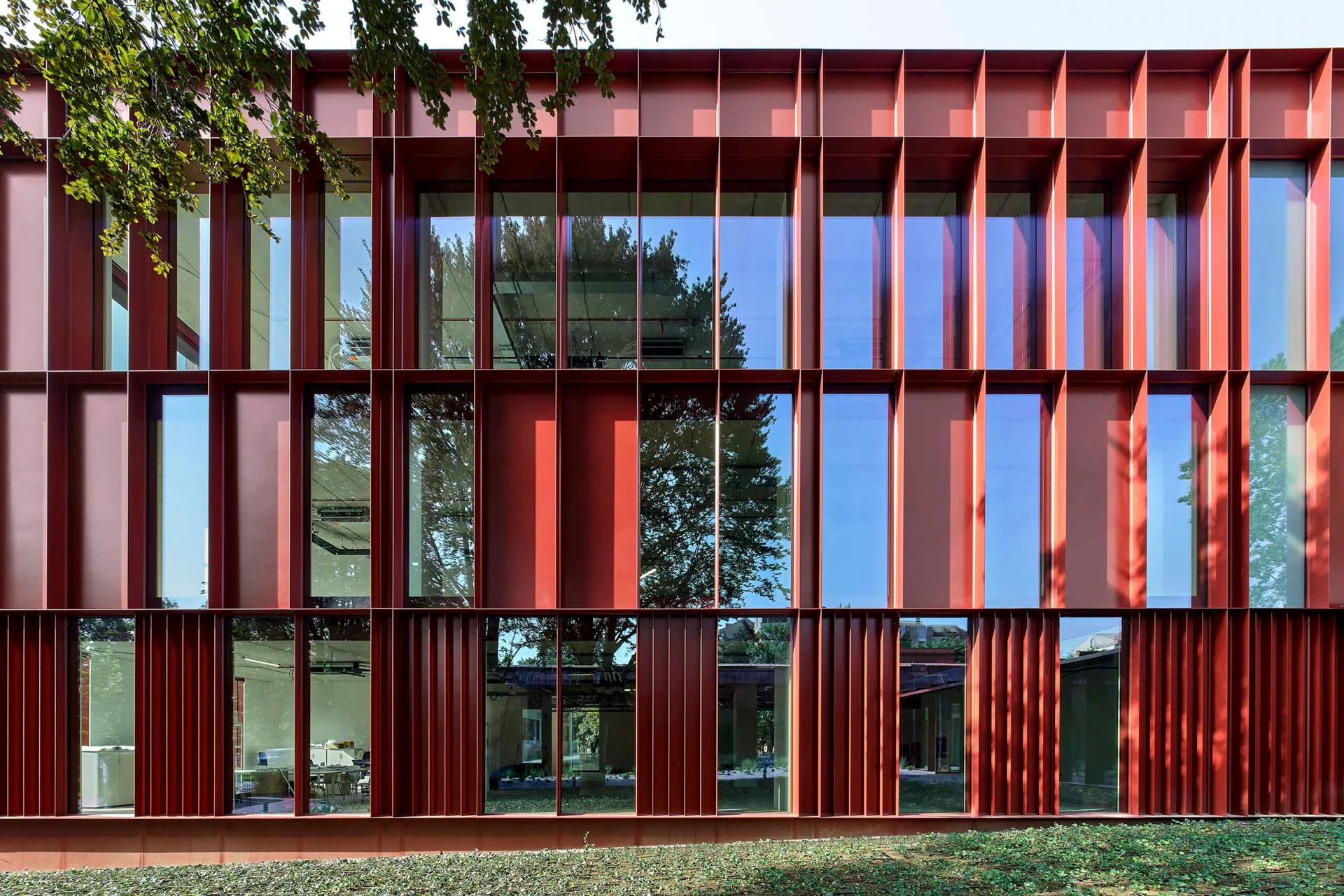Ein weit auskragendes Brise-Soleil aus rot beschichtetem Blech strukturiert die Fassaden des aufgestockten Kopfbaus.