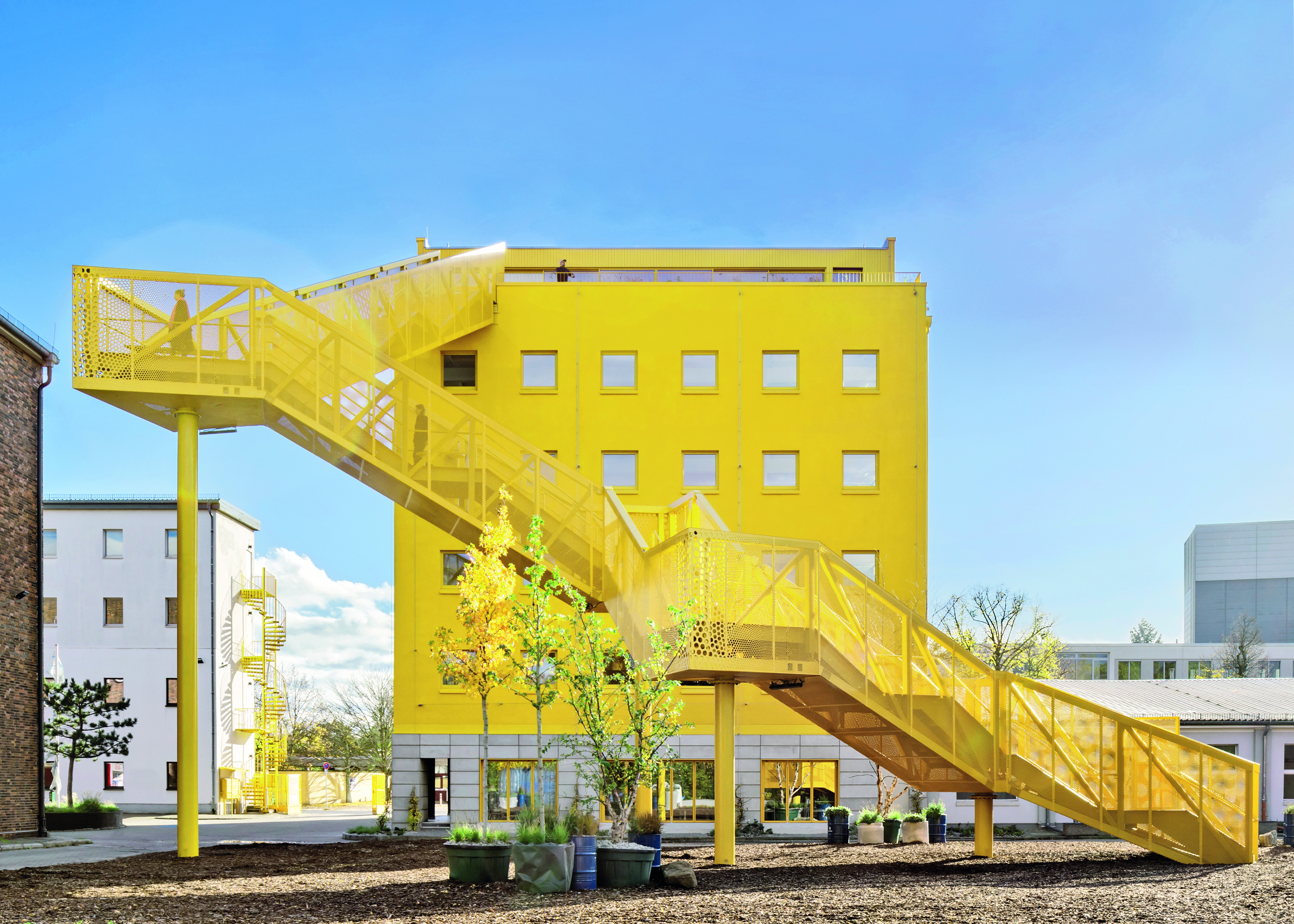 Bright yellow landmark on the Atelier Gardens campus: the zigzag staircase with seating and viewing platforms leads up to the roof terrace.