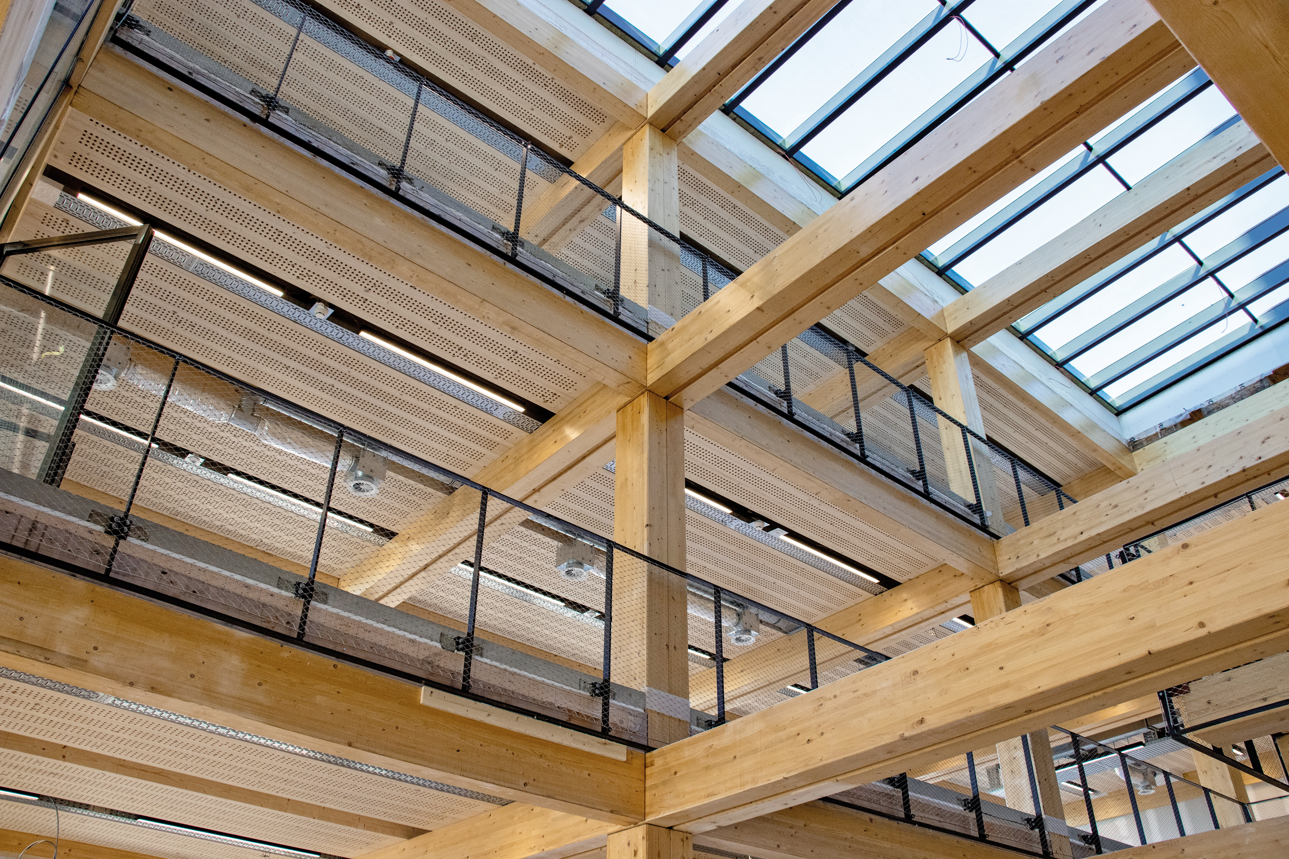 Besonders im Atrium lässt sich das Zusammenspiel der Holztragkonstruktion ablesen. Je zwei Brettschichtholzträger pro Stützenachse tragen die Decken.