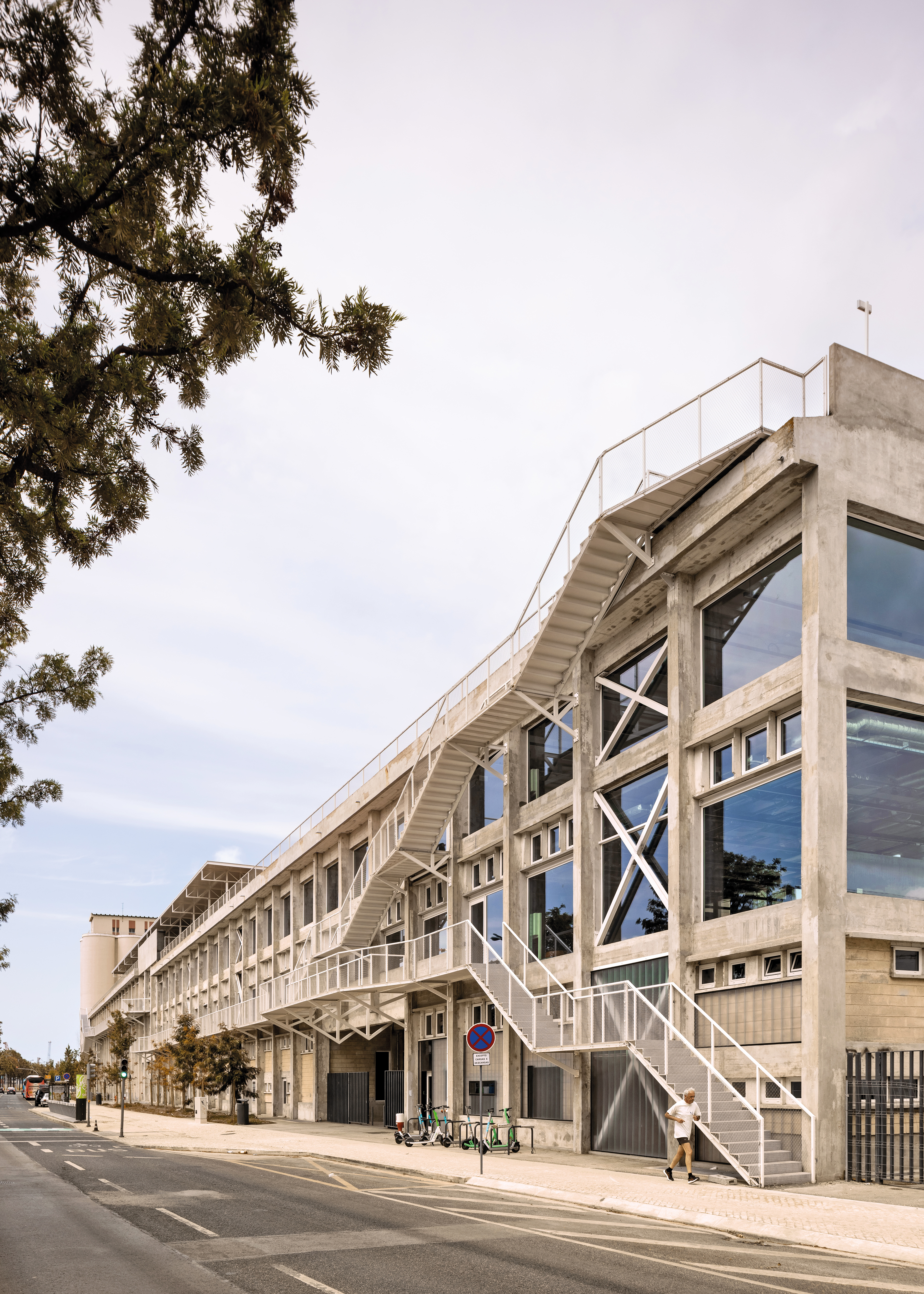 Following the renovation, steel staircases and balconies line the exterior of the 200 m long former factory building. The central space with its grain silos serves as the lobby and features staircases and elevators.