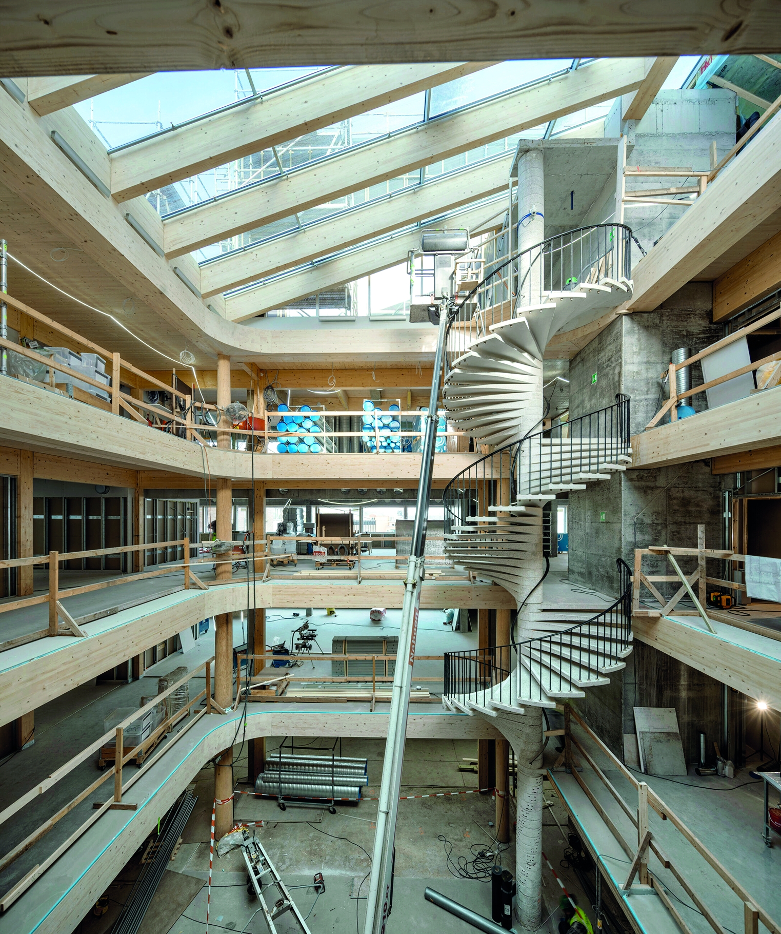 Die neuen Einbauten rund um das Atrium bestehen weitgehend aus Holz. Erhalten geblieben ist die einstige Fluchttreppe, die nach wie vor die Etagen miteinander verbindet.