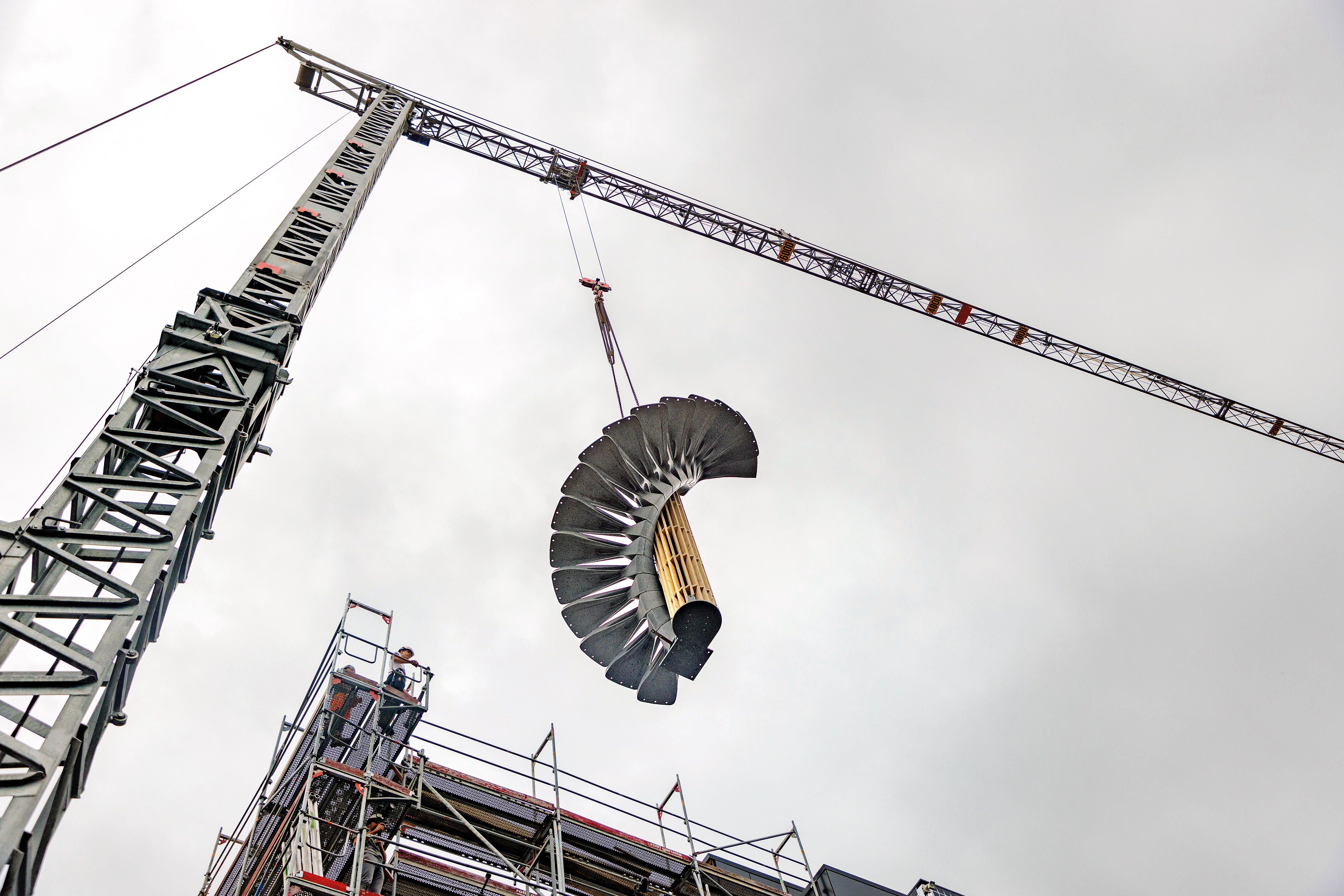 Die vormontierte und vorgespannte Treppe wird in einem Stück in ihre Position auf der Baustelle gehoben.