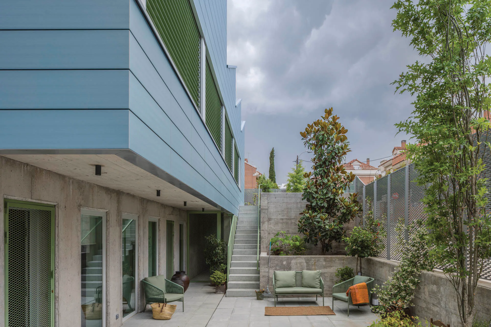 Unten ist das barrierefreie Apartment untergebracht, oben die Maisonettwohnung. Die zur Straße hin orientierten Außenräume sind über eine Treppe miteinander verbunden.