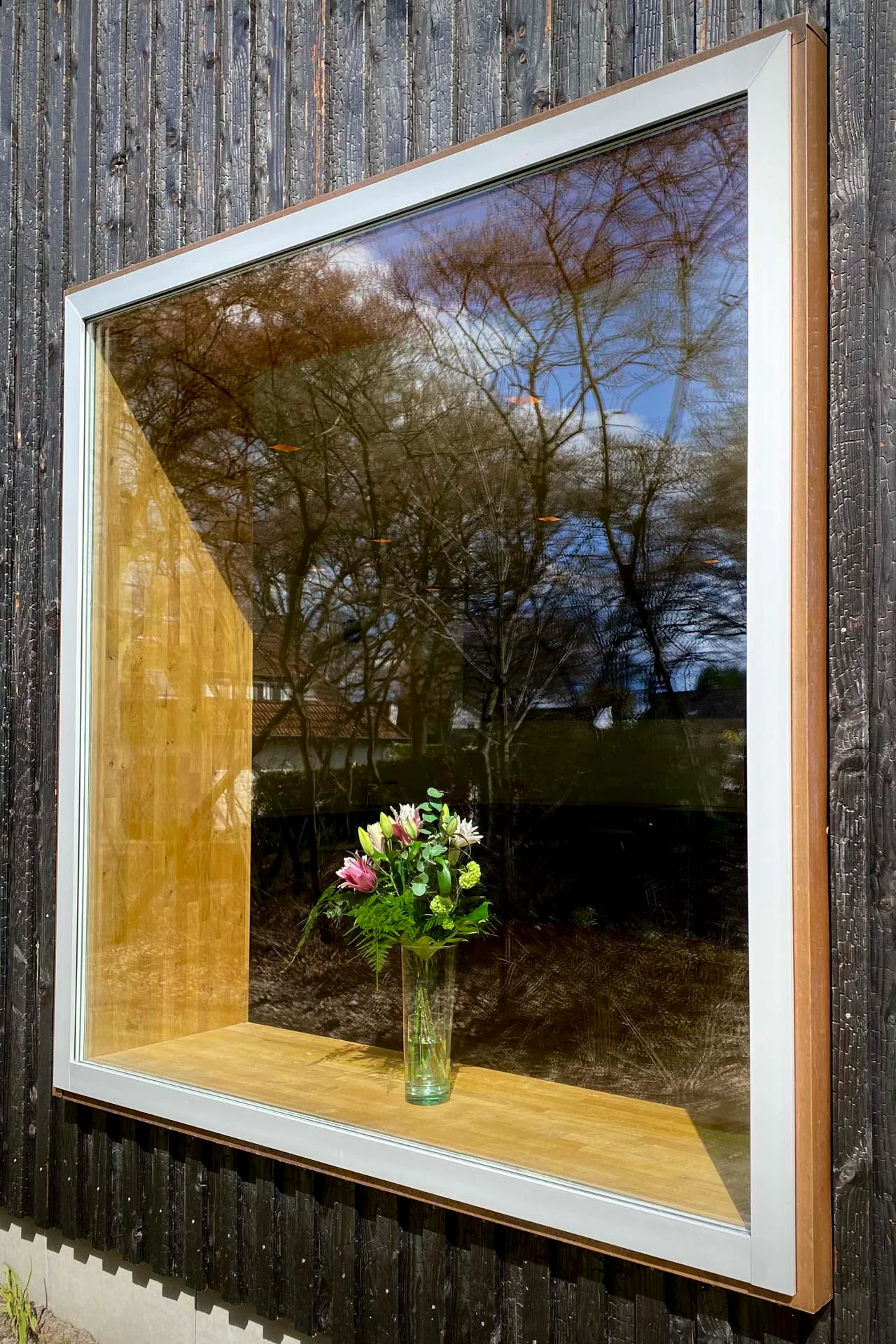 Die auskragenden Elemente der bis zu 4 m hohen Fensterscheiben treiben die Tradition des Blumenfensters auf die Spitze. Ein frischer Strauß signalisiert Einbrechern, dass das Gebäude bewohnt ist.
