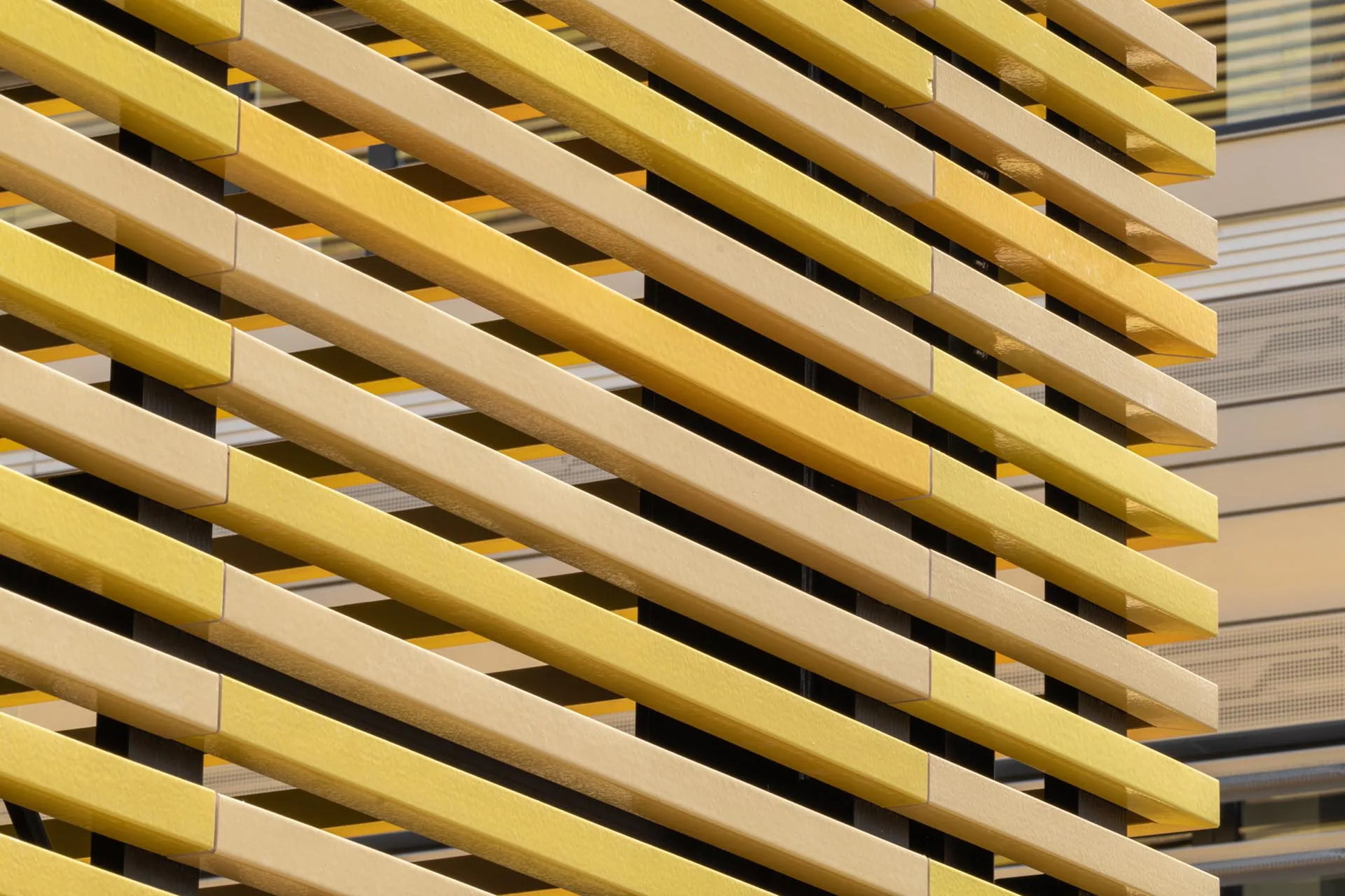 Fassadenbekleidung aus quadratischen, hohlen Keramikstäben, sogenannten Baguettes, in fünf Gelbtönen (RAL 1002, 1004, 1012, 1018 und 1021).