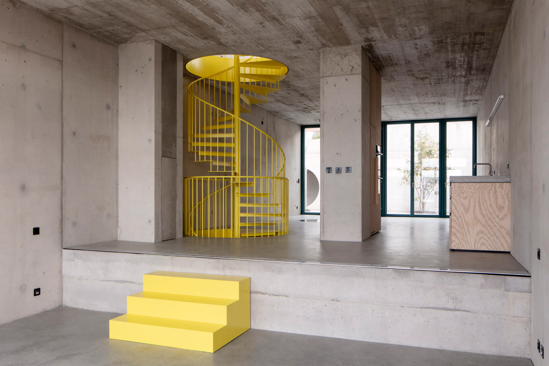 Innen sind Treppen, Küchenzeilen und Bäder in starken Farben von der Sichtbetonstruktur abgesetzt.