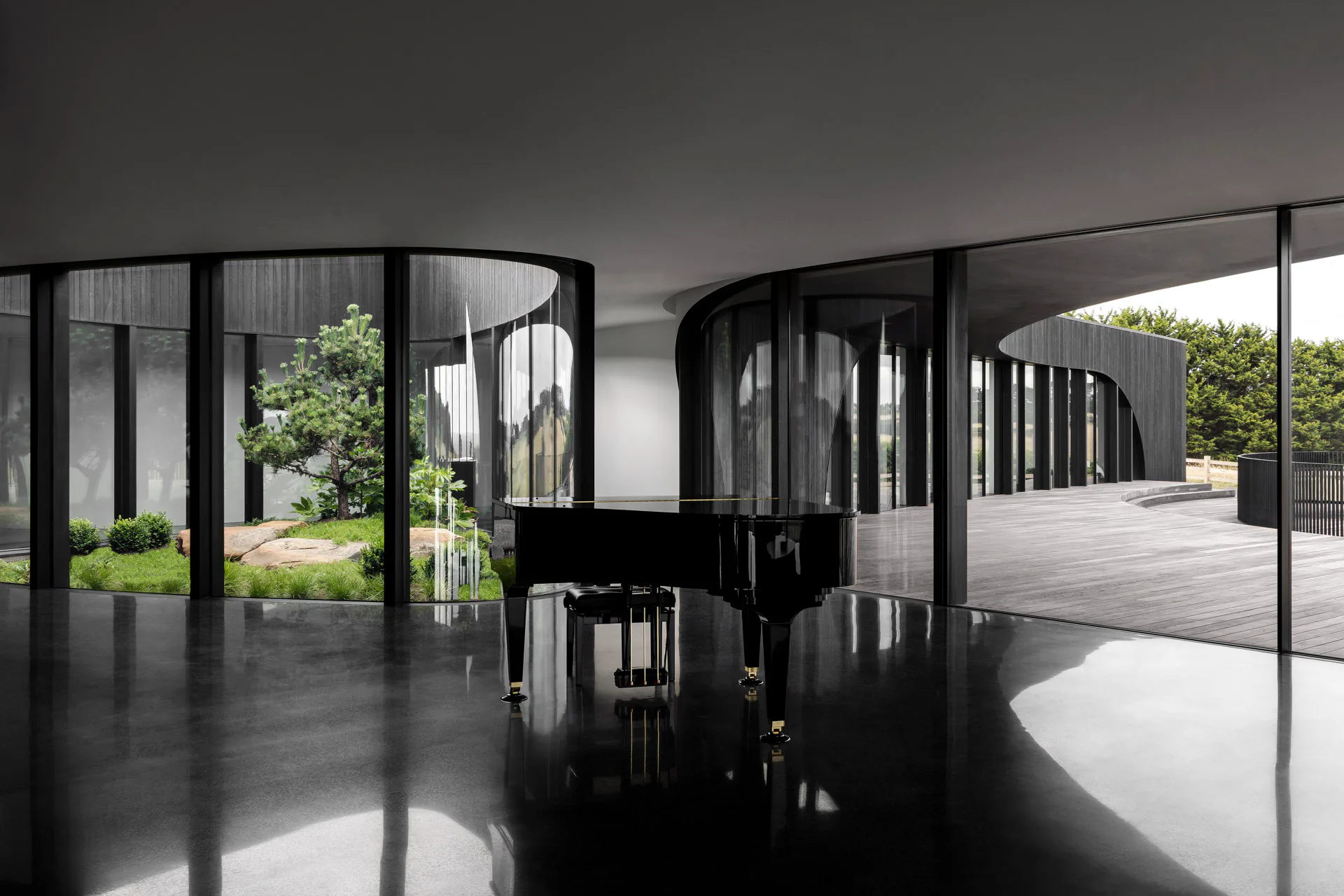 Ein monochromes Design definiert die Innenräume. Ein bepflanztes Atrium und große Glasflächen bringen Tageslicht in den Wohnbereich.