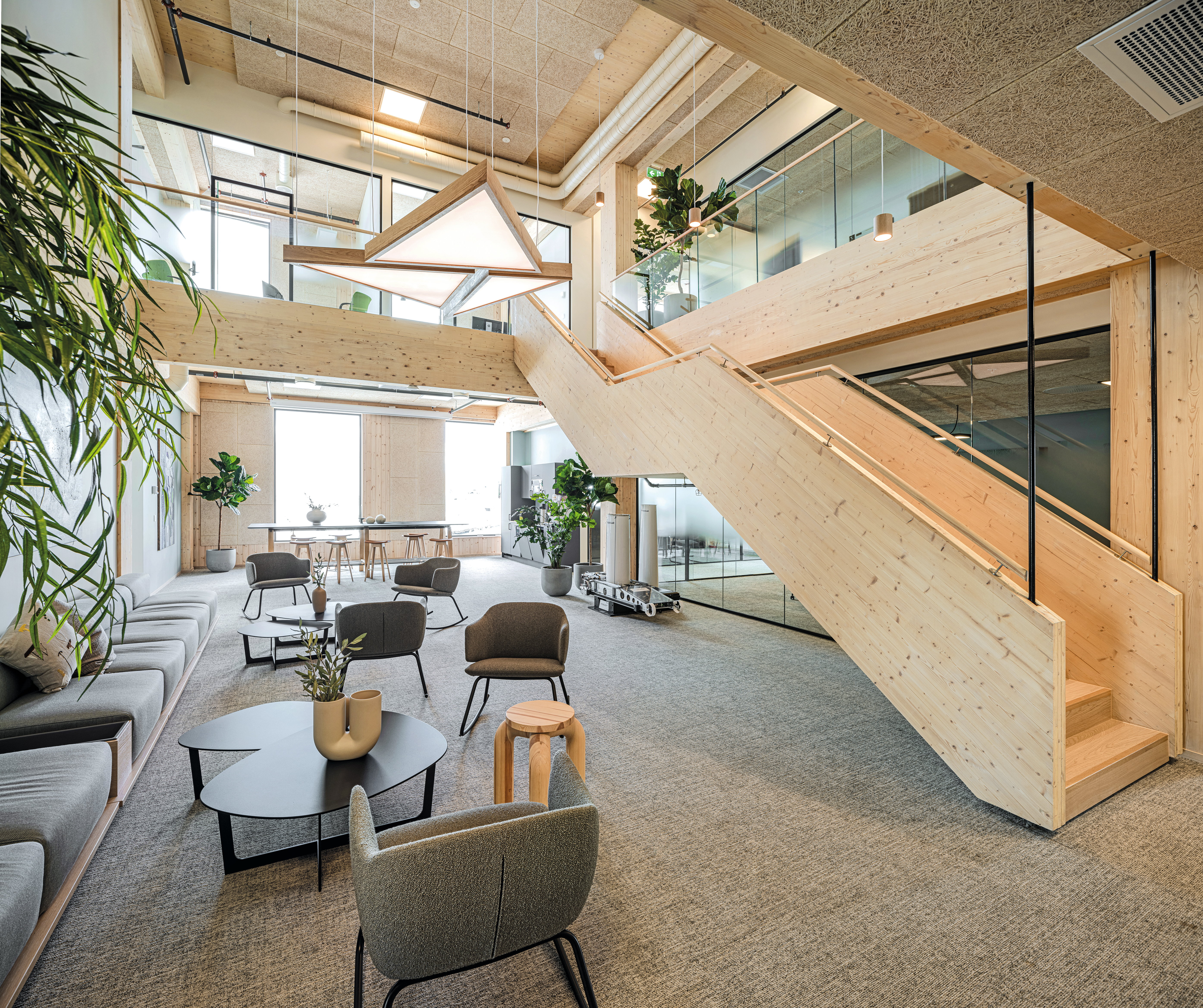 Das zweigeschossige Atrium in den Obergeschossen bietet viel Raum für Gemeinschaft. Eine massive Treppe aus Brettschichtholz führt nach oben auf die Galerie.