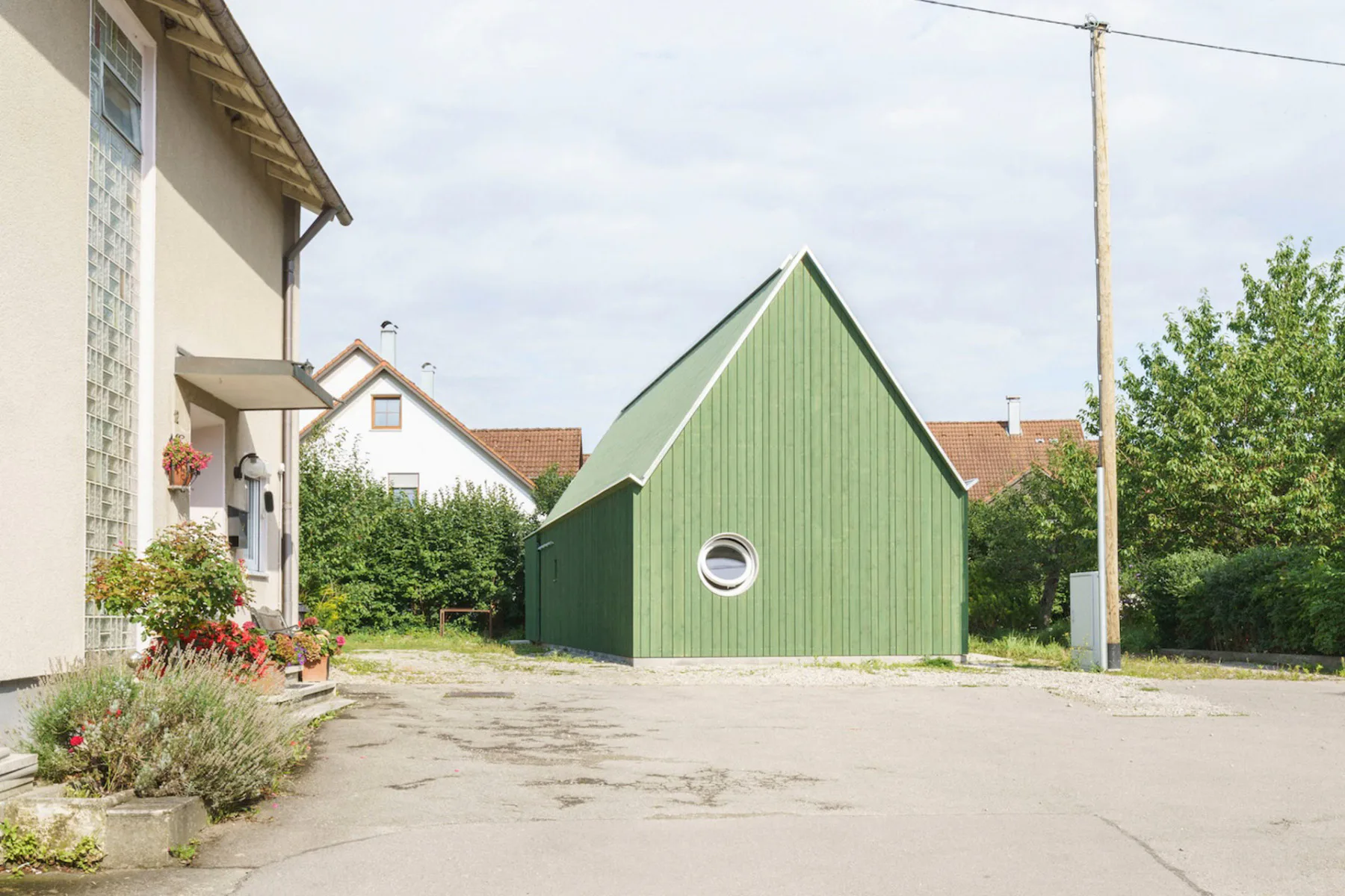 Mit seinem markanten Satteldach und der grünen Farbe bildet das Ateliergebäude einen Farbtupfer im Ortskern.
