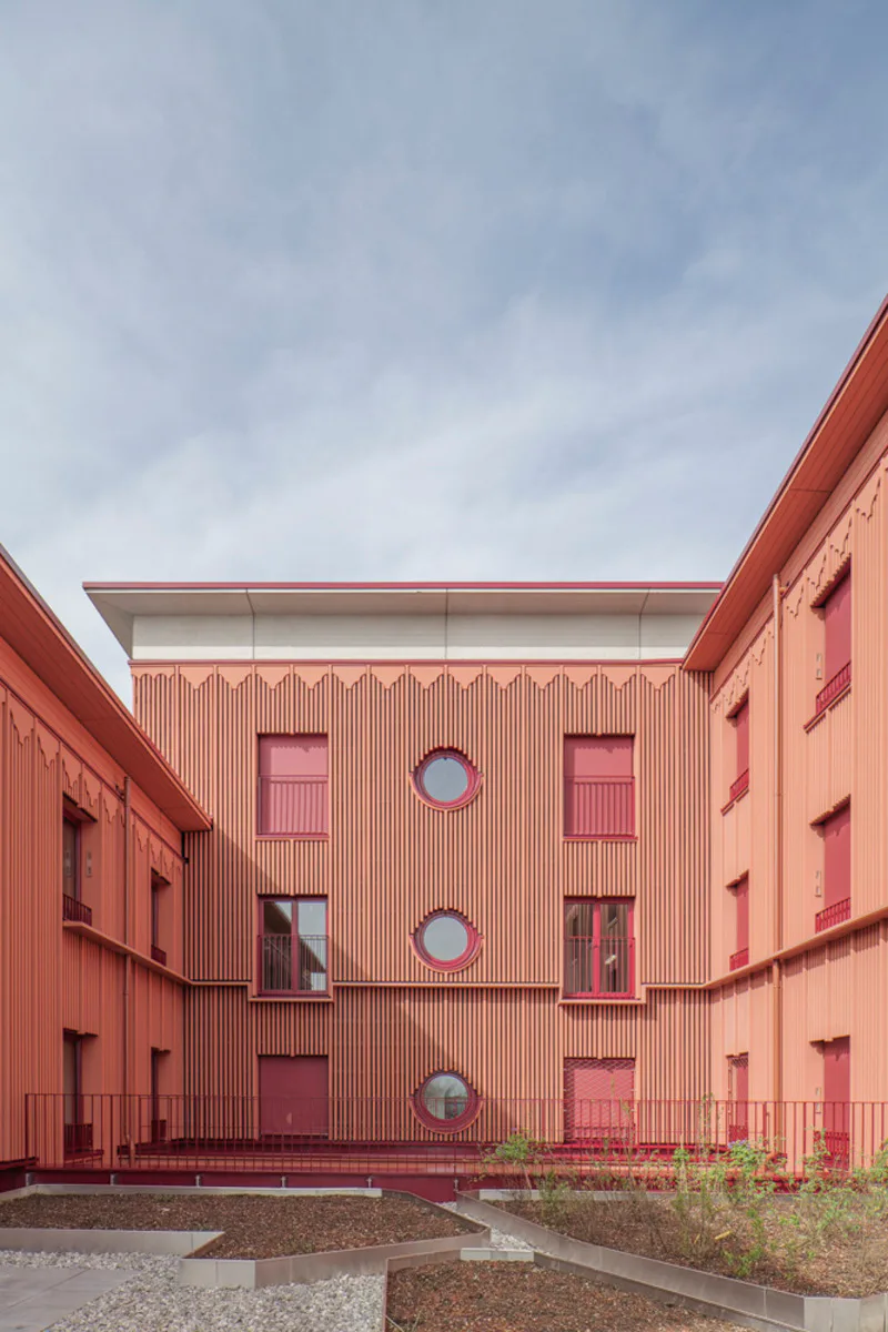 Die ziegelrote Fassade mit Betonattika