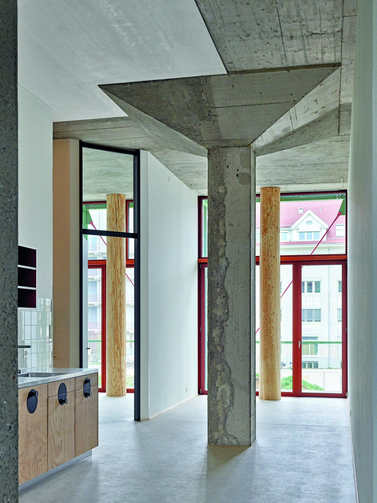 Mächtige Pilzstützen stehen mitten im Raum. An der Fassade kompensieren geschälte Baumstämme den Wegfall der tragenden Brüstungen. Eine ausführliche Dokumentation zum Projekt finden Sie in Detail 5.2024.