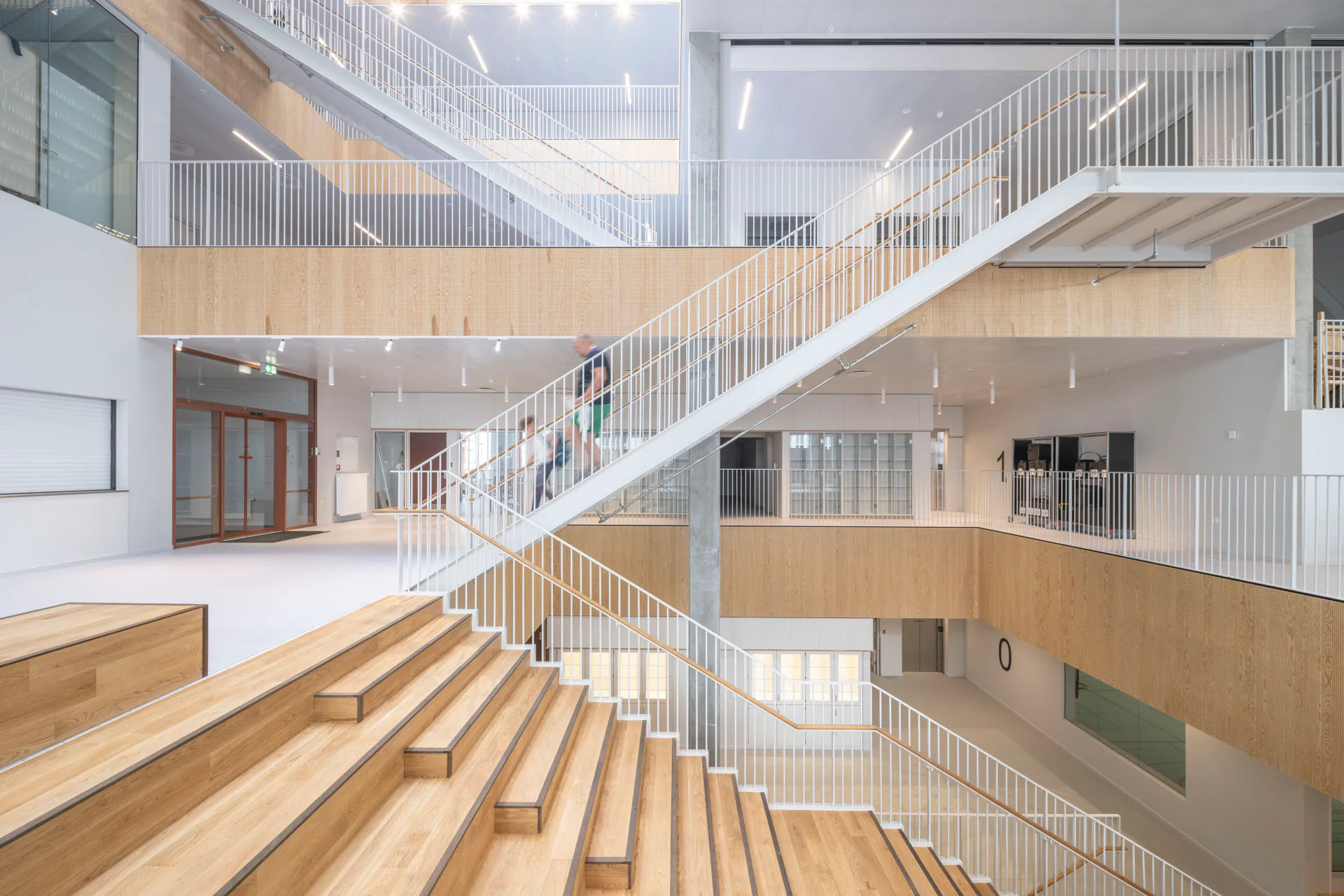 Eine von oben belichtete Treppenkaskade führt aus dem Atrium hinauf in die Obergeschosse.