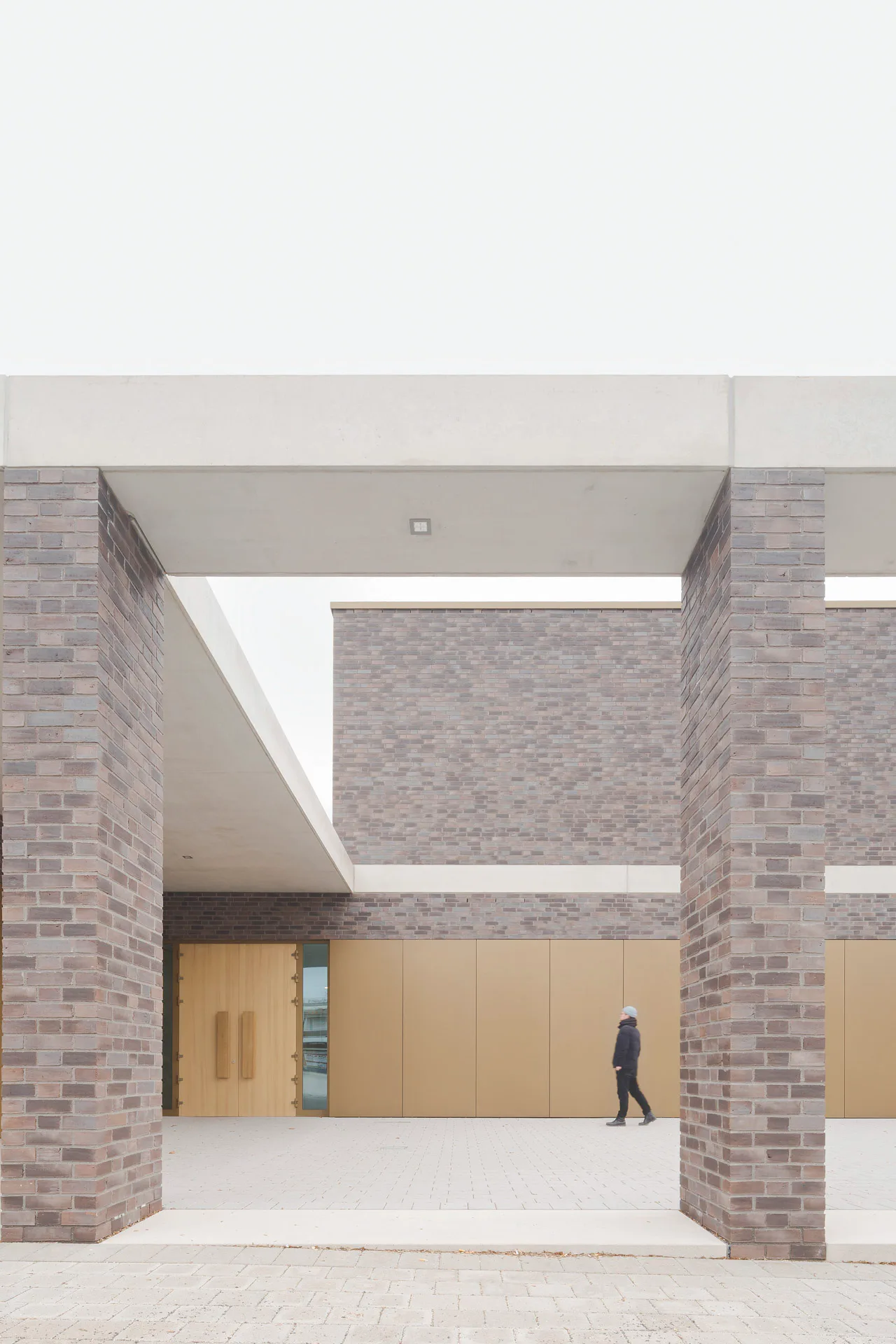 Ein Sichtbetonband zieht sich durch die Fassade des gesamten Gebäudes. Am Anbau wird es als Attika fortgesetzt und überdacht Eingangsbereich und Pergola.