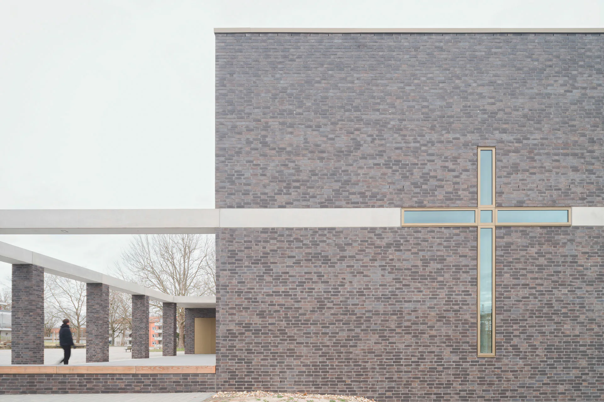 Ein Glaskreuz an der Südfassade unterbricht die horizontale Linie des Sichtbetonbands.