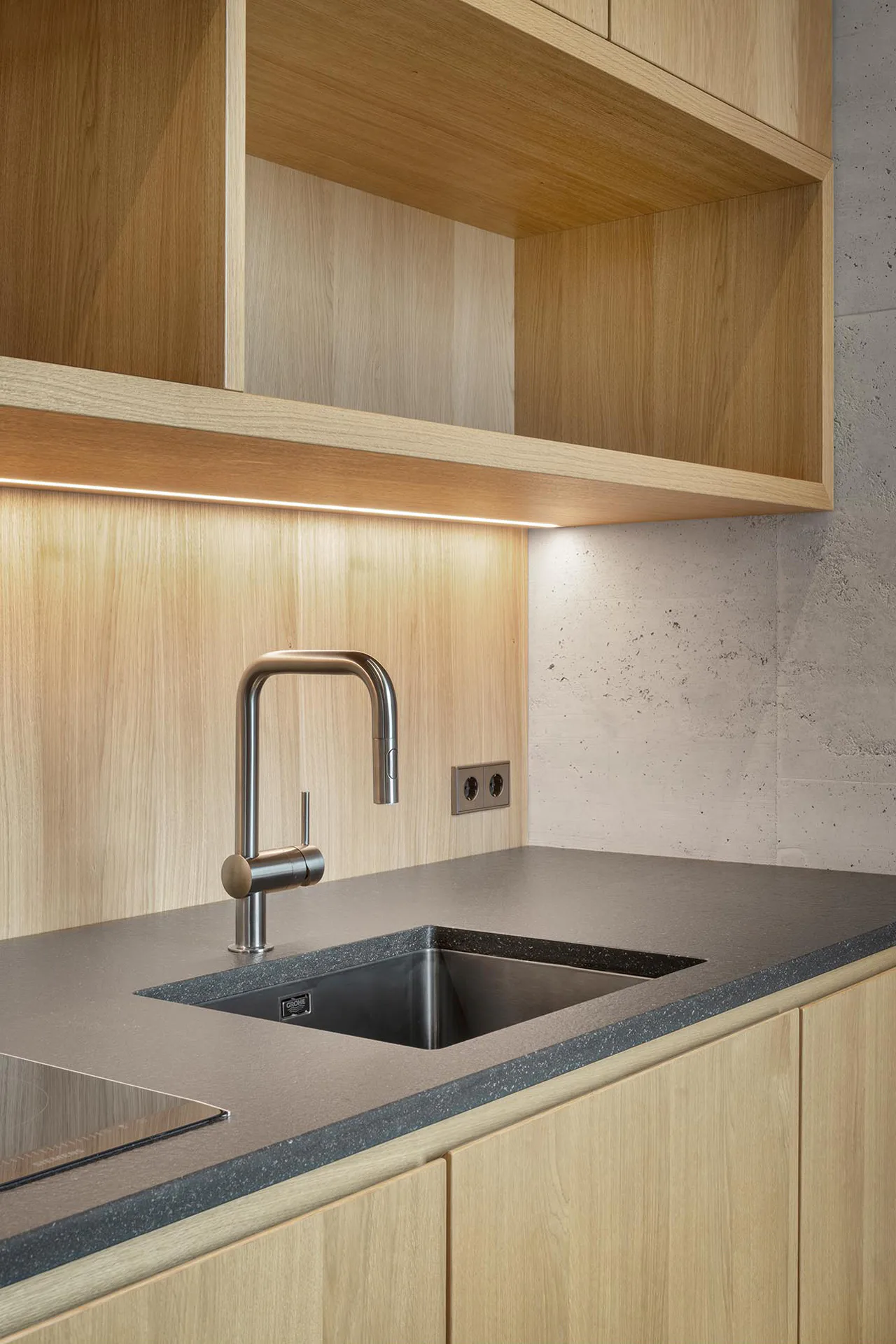 Die Grohe Minta Küchenarmatur mit ihrer Oberfläche in gebürstetem Hard Graphite rundet den Materialmix aus Holz, Stein und Beton in der Küchenzeile ab.