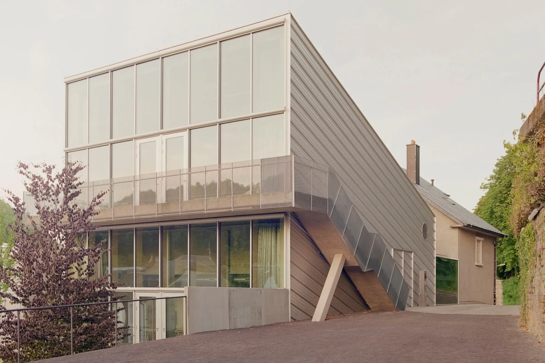 Das neue Ateliergebäude überragt den Altbau deutlich und setzt mit seiner Glas- und Metallhülle einen unverkennbar zeitgenössischen Akzent.