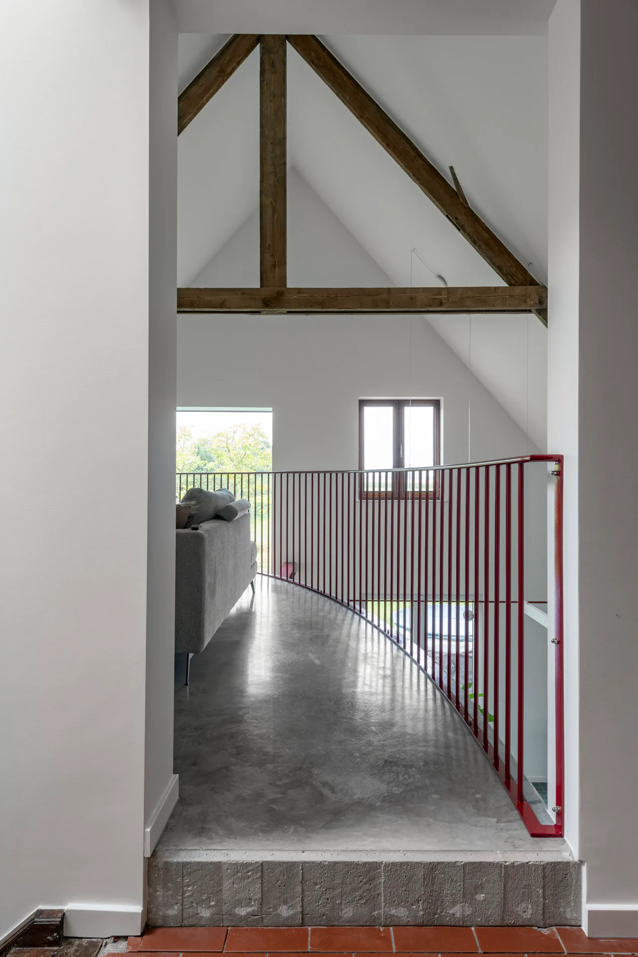 Subtile Kontraste bestimmen den Innenraum: Auf der Galerie begegnen sich das dreieckige Hängewerk der Dachkonstruktion und die viertelkreisförmige Galerie.