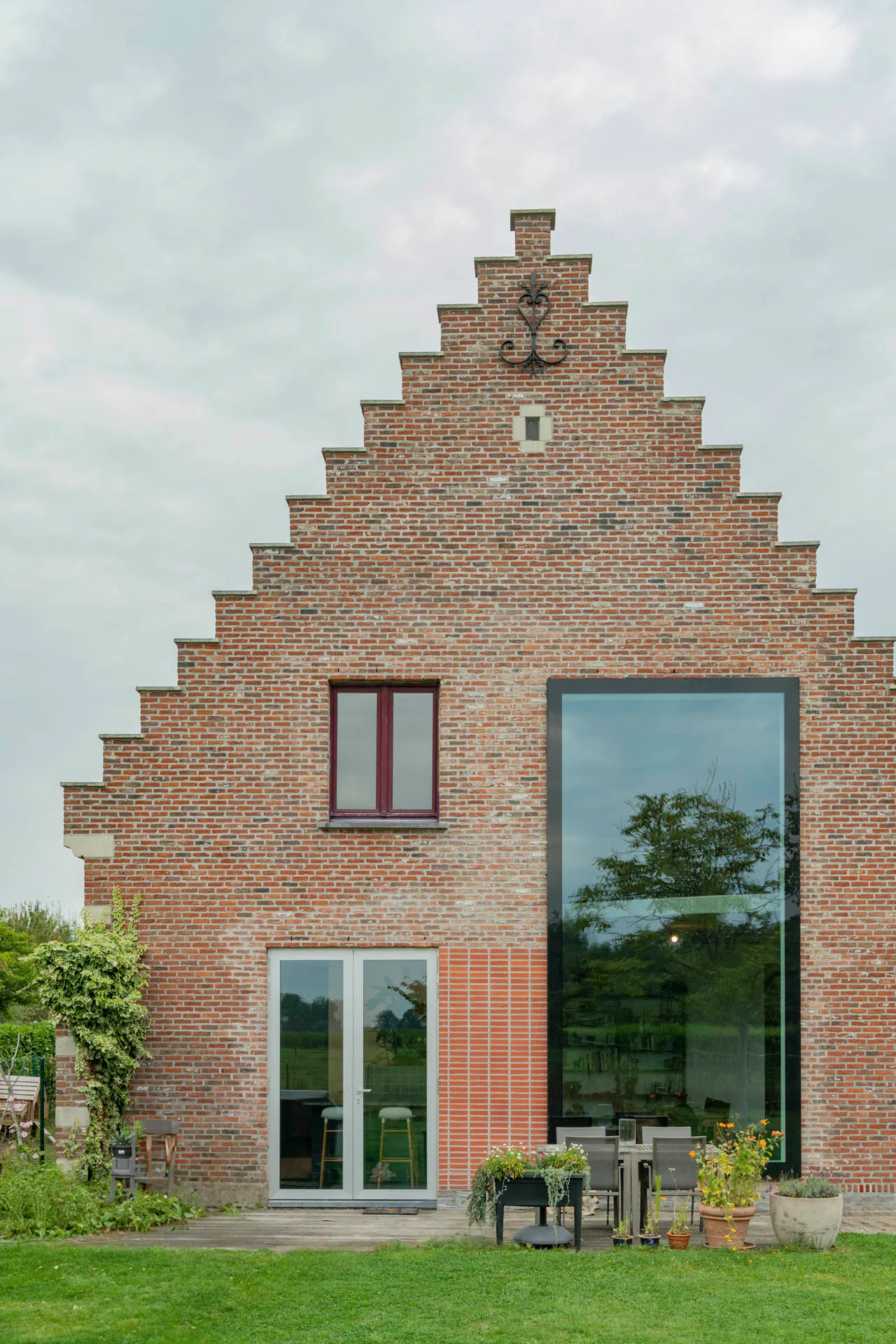 Der Stufengiebel wurde fachgerecht restauriert. Ein neues, großformatiges Fenster verbindet den Wohnraum mit dem Garten.