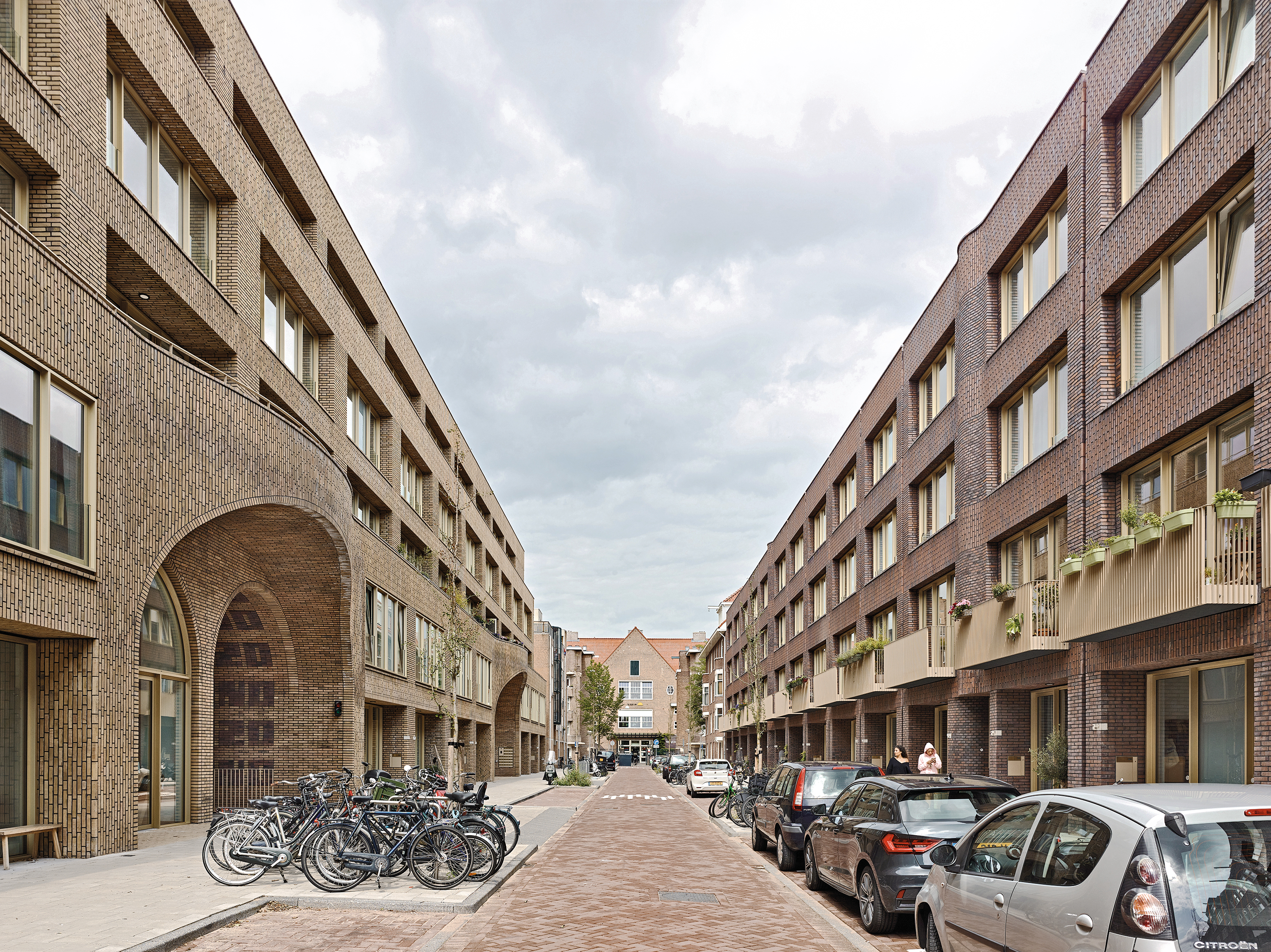 The arched portals to the courtyard highlight the curved brick facade along the street. The courtyard-facing facades are clad in pale green tiles.