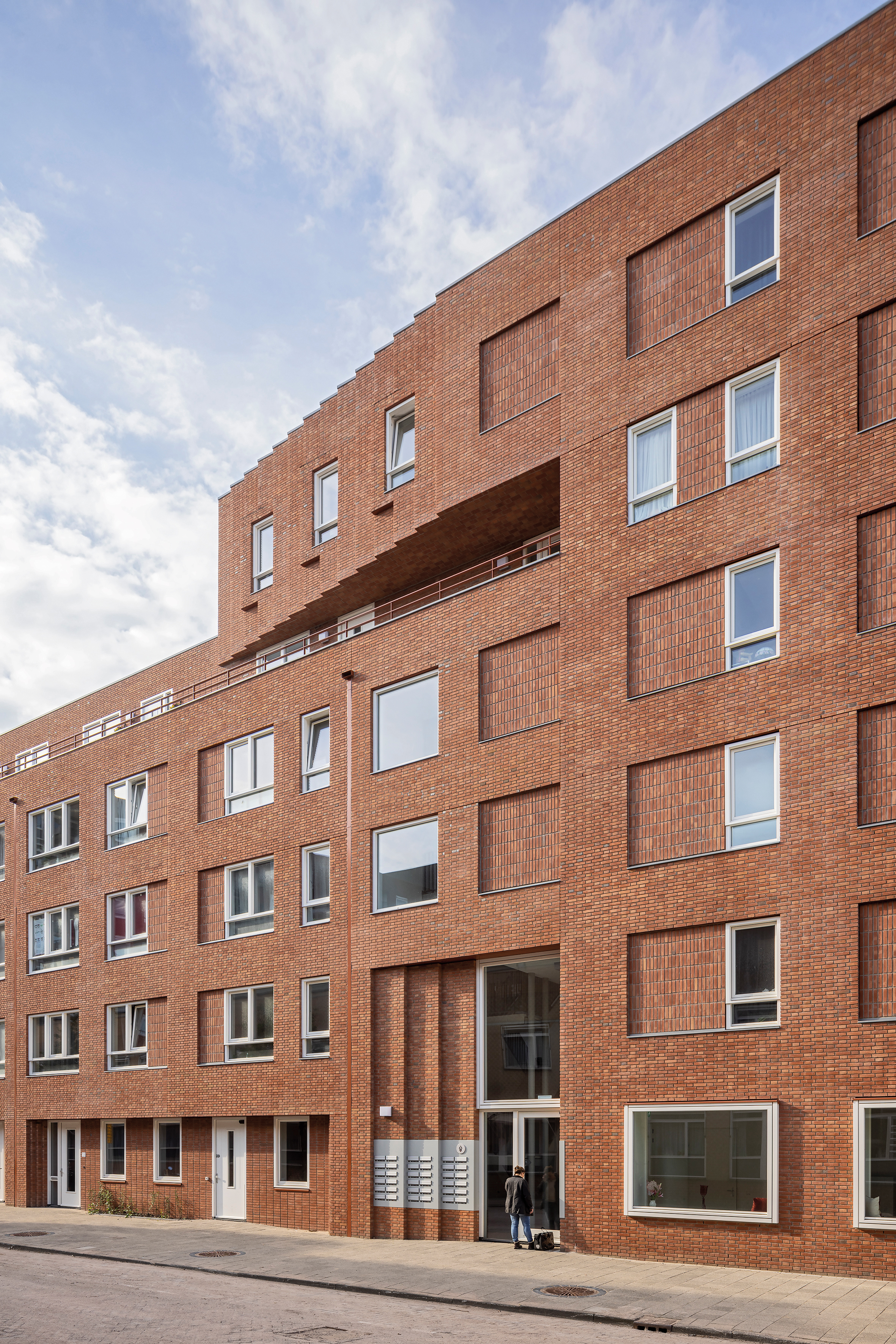 The upper floors feature apartments with outdoor walkway access for seniors. The ground floor houses family units with courtyard gardens and a shared community room.