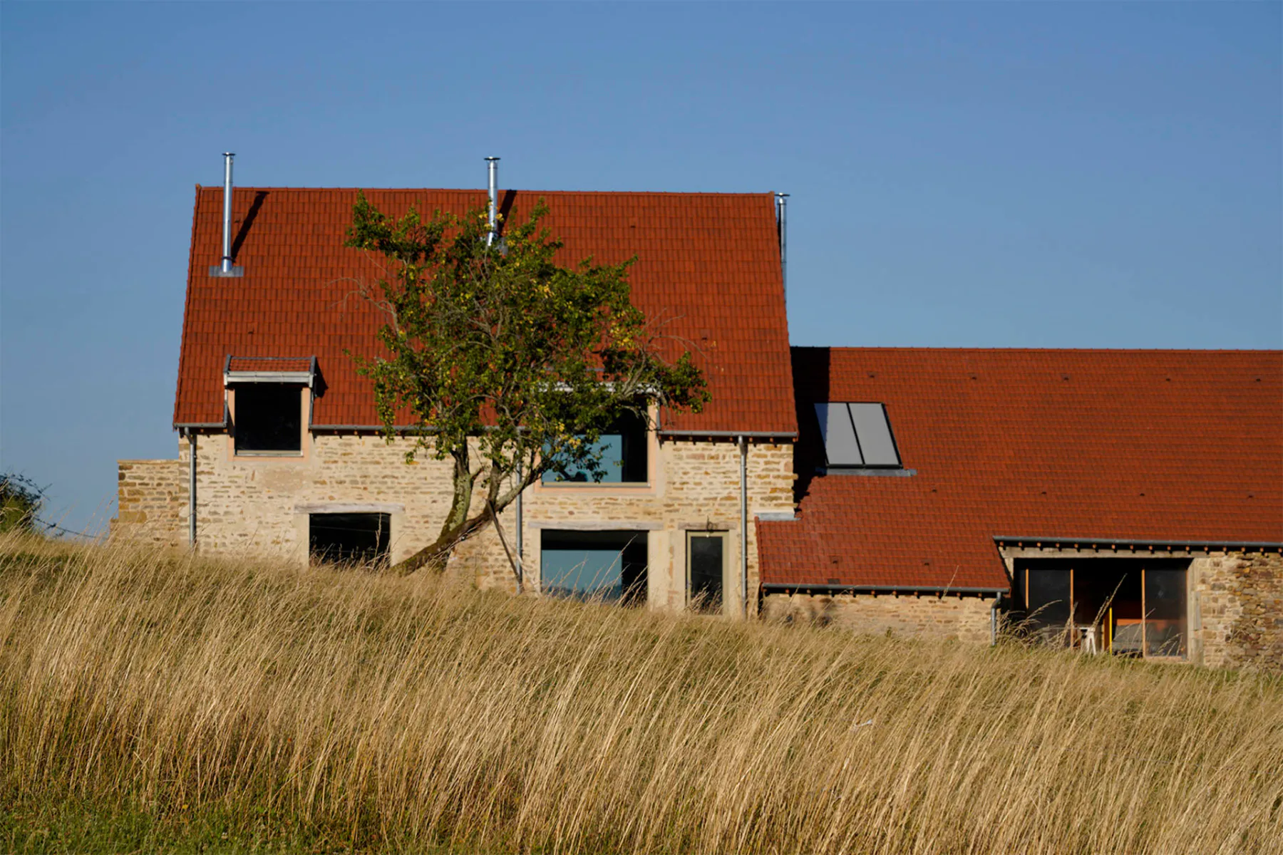 Das alte Bauernhaus öffnet sich mit deutlich größeren Fenstern nach außen als zuvor. Die charakteristische Natursteinarchitektur blieb jedoch erhalten.