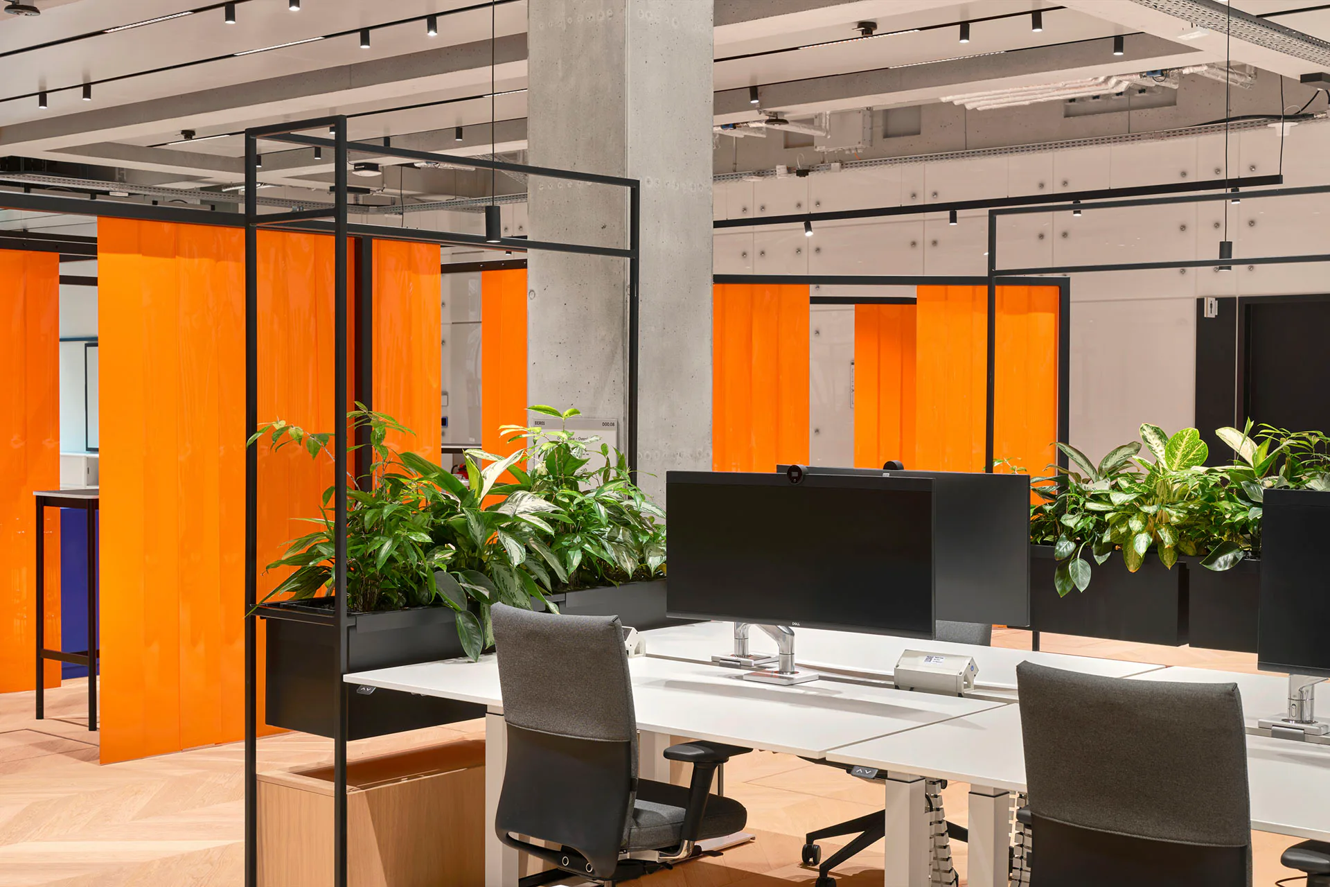 Der Open-Office-Bereich wird durch orangefarbene PVC-Lamellenvorhänge unterteilt.