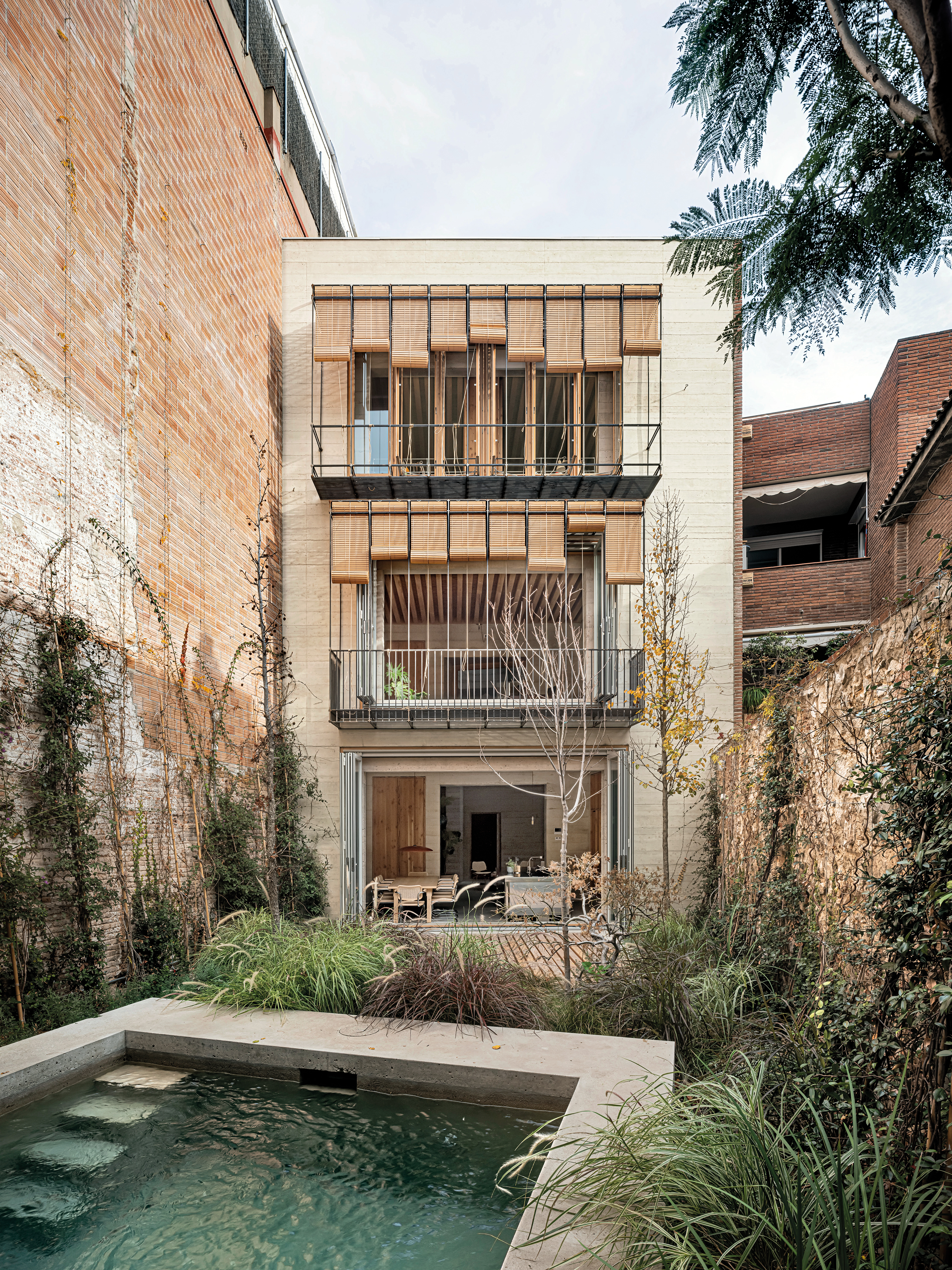 Die rückwärtige Fassade öffnet sich mit Balkonen und einer Terrasse zum Garten, einer grünen Oase in der Stadt.