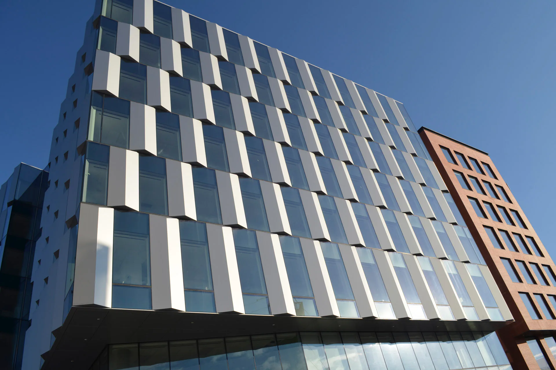 Aluminium-Wabenkernpaneele lassen sich unter anderem zu Elementfassaden, Verschattungselementen und Freiform-Fassadenverkleidungen verarbeiten.