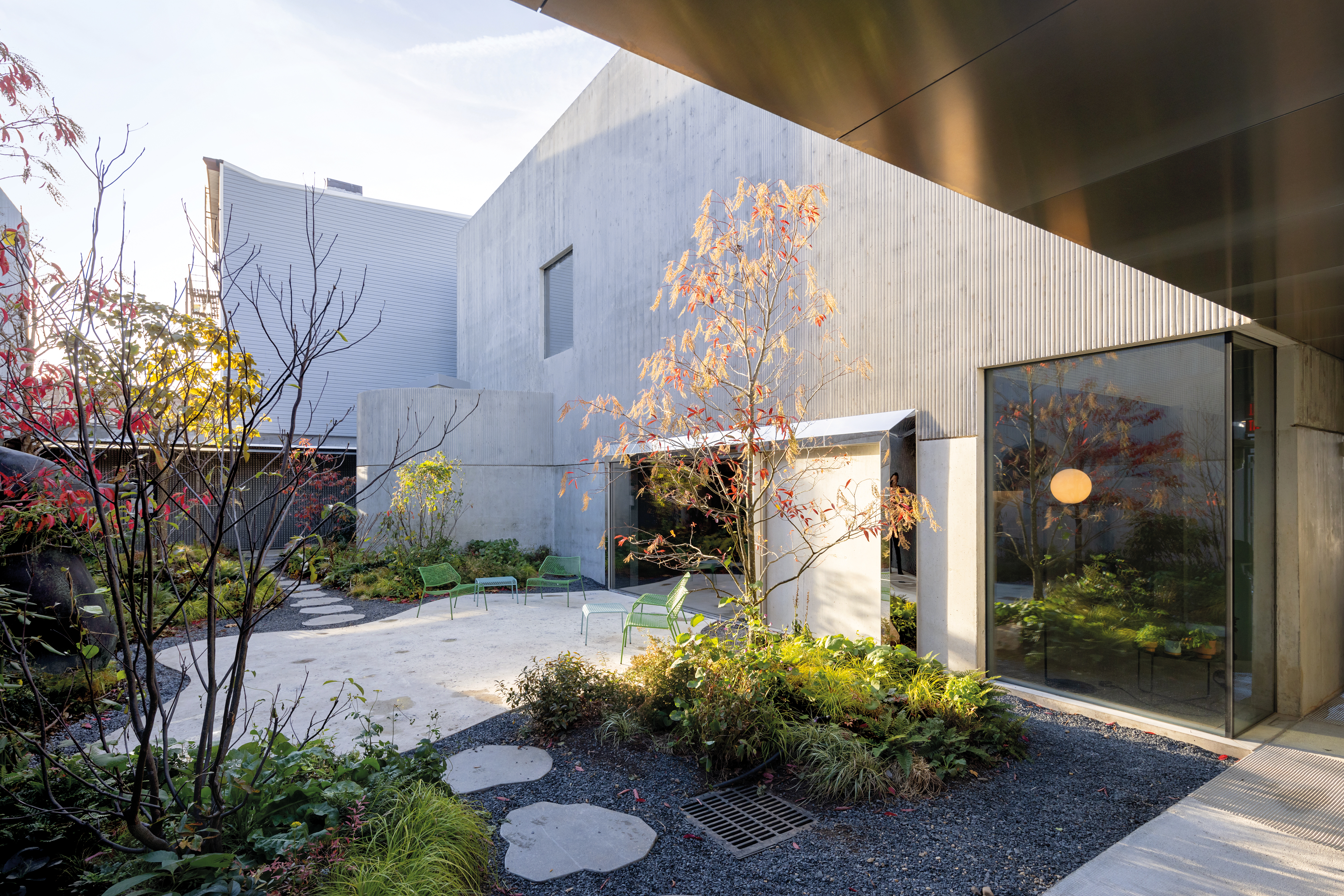 Fassaden aus fein profiliertem Sichtbeton begrenzen im Bereich der Gastateliers für Kunstschaffende einen Innenhof, der an einen japanischen Garten erinnert.