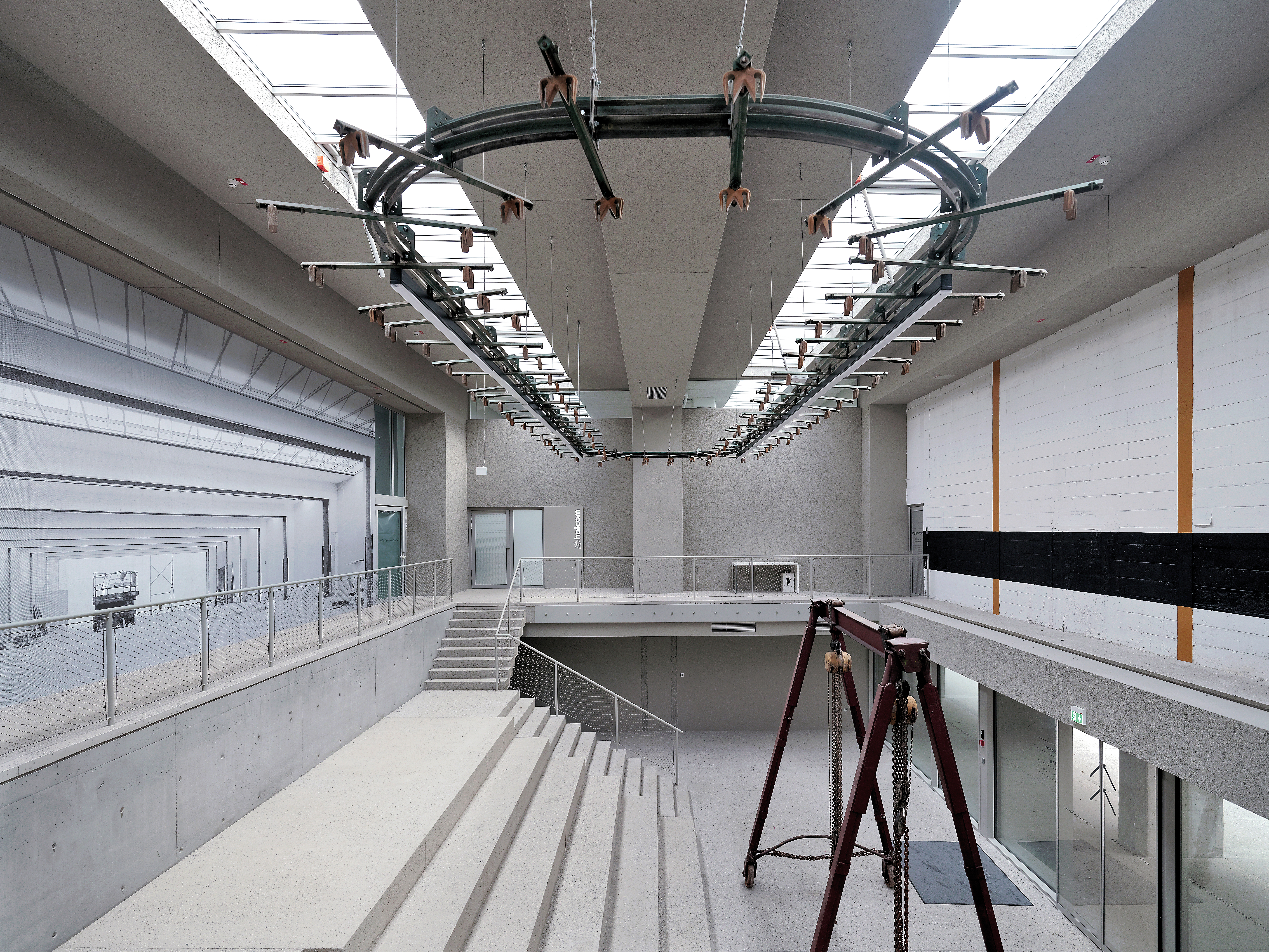 In der zweigeschossigen Eingangshalle wurden Fundstücke aus dem Altbau wiederverwendet − etwa beim Kronleuchter, der aus alten Förderbändern für den Zeitungsdruck besteht.