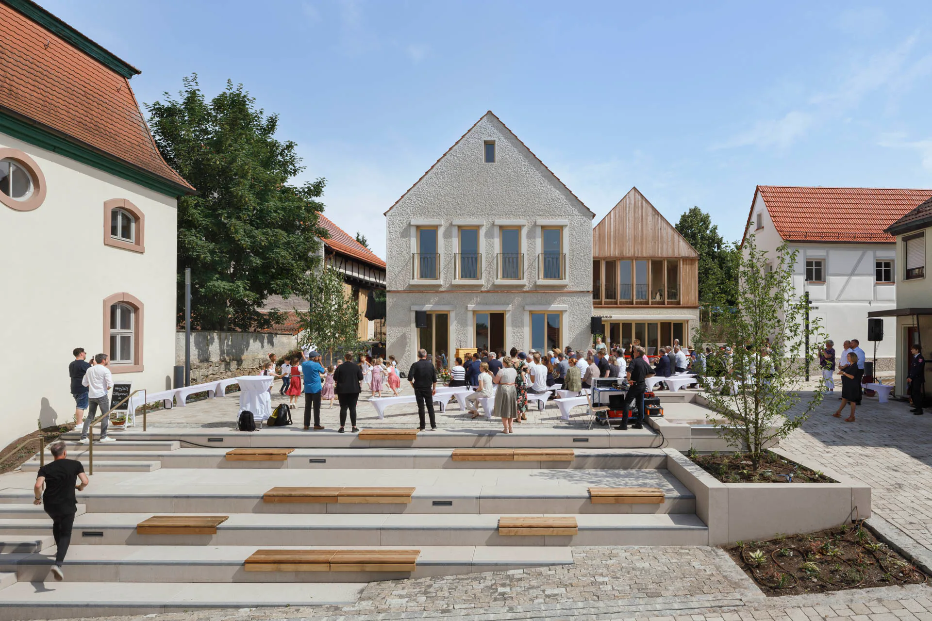 Zwei Neubauten aus Holz und Recyclingbeton ergänzen drei Bestandsbauten als Ort der Begegnung.