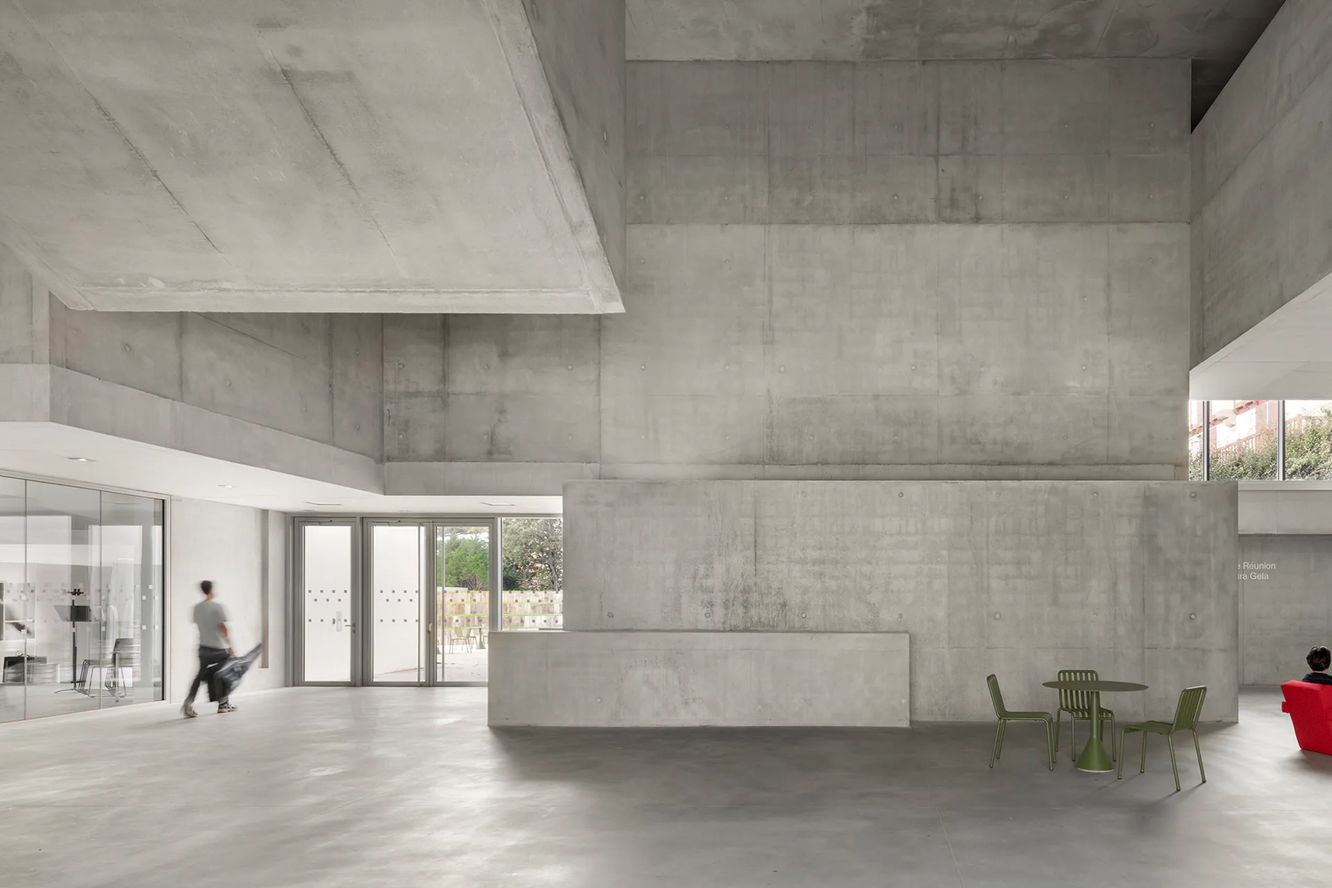 Im Inneren erwartet die Besucher ein dreigeschossiges Atrium fast ganz aus Sichtbeton, in das Tageslicht von allen Seiten fällt.