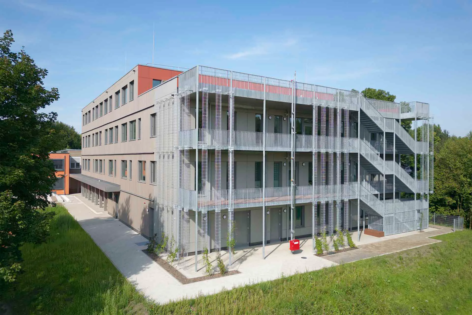Die Fassade des Neubaus ist mit vertikalen Holzlatten verkleidet und mit einer Grünfassade kombiniert.