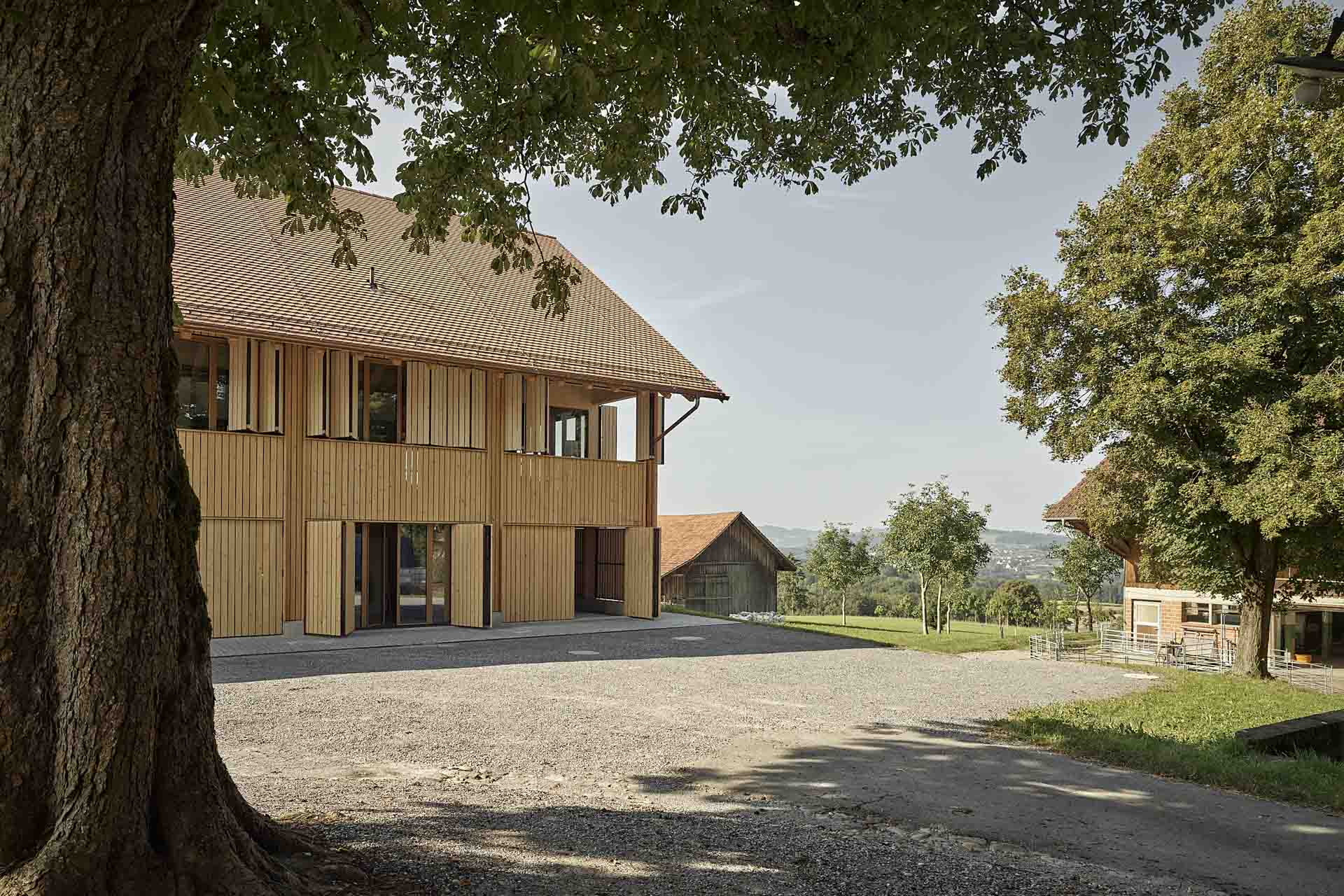 Um den Eindruck einer umlaufend geschlossenen Gebäudehülle – wie bei einer Tenne – herzustellen, erhielt das Wohnhaus Faltläden mit der gleichen Lattenschalung wie die Holzfassade.