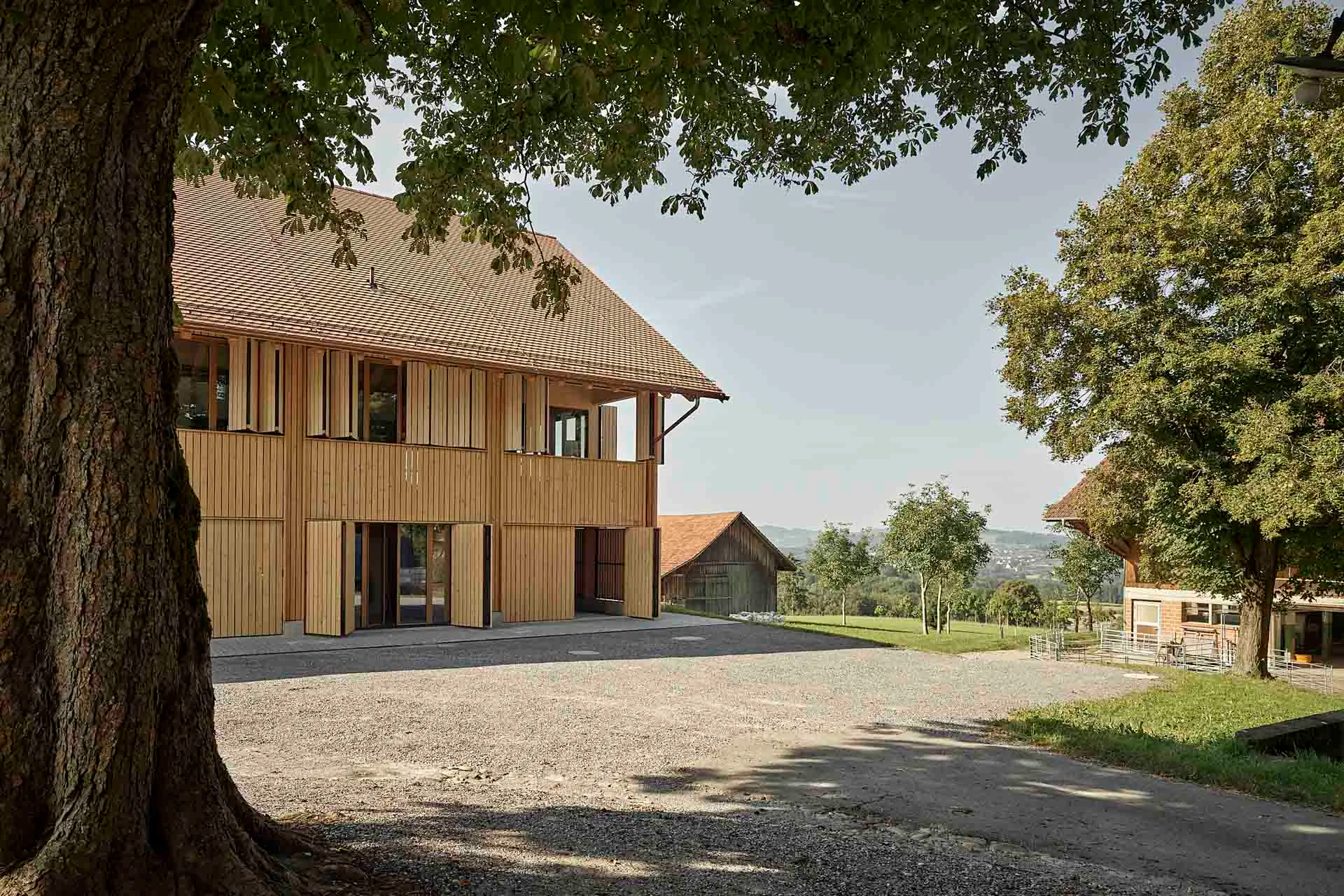 Um den Eindruck einer umlaufend geschlossenen Gebäudehülle – wie bei einer Tenne – herzustellen, erhielt das Wohnhaus Faltläden mit der gleichen Lattenschalung wie die Holzfassade.